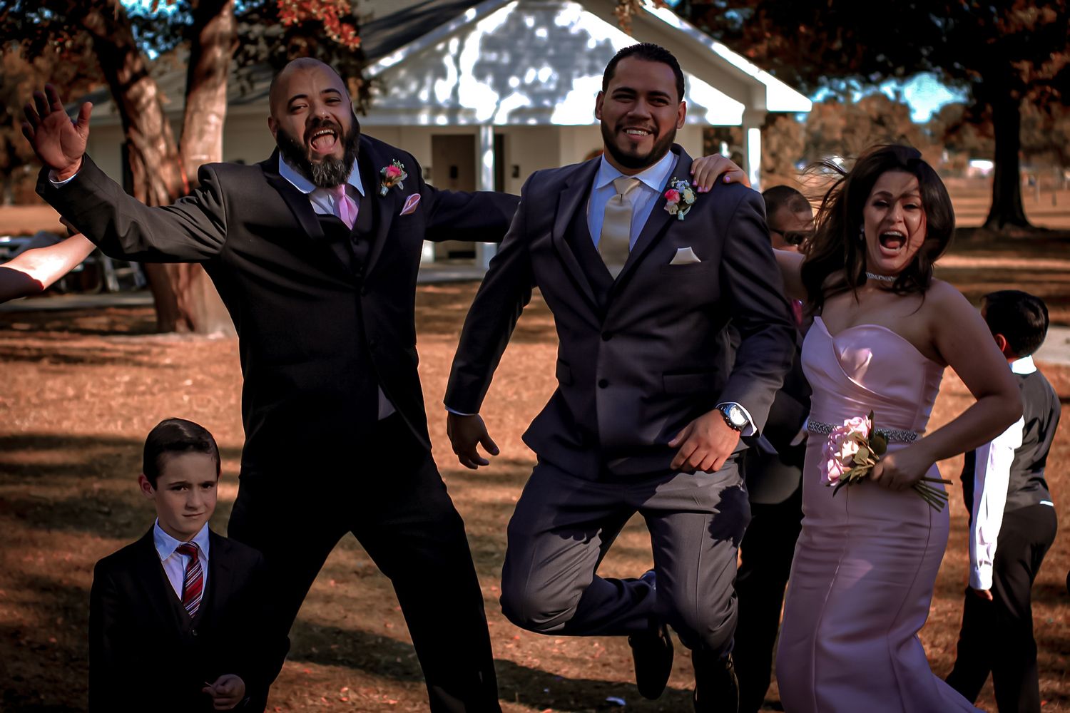 Group posing playfully outdoors in formal attire at sunset.