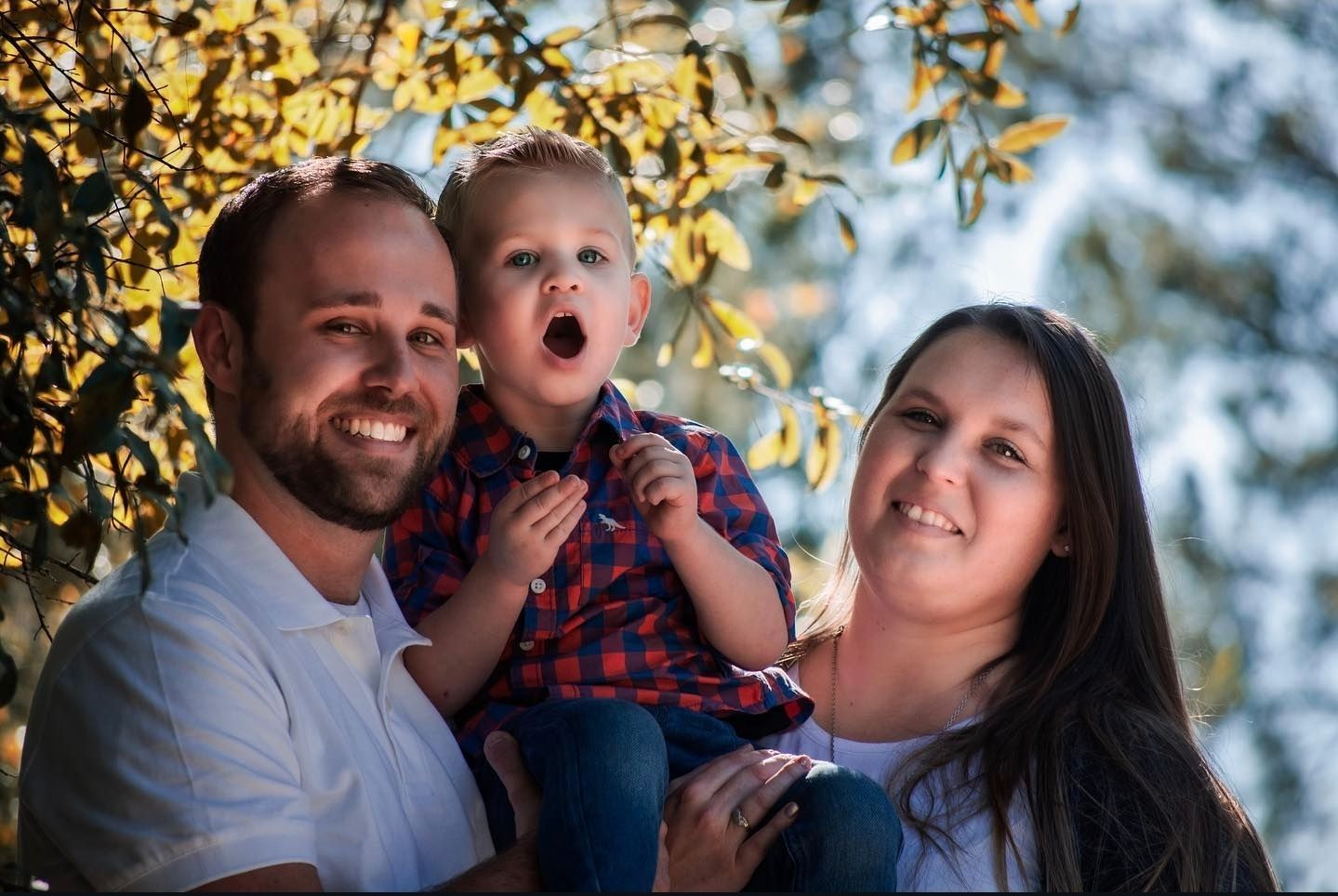 Family portrait captured at sunset with autumn foliage in the background.