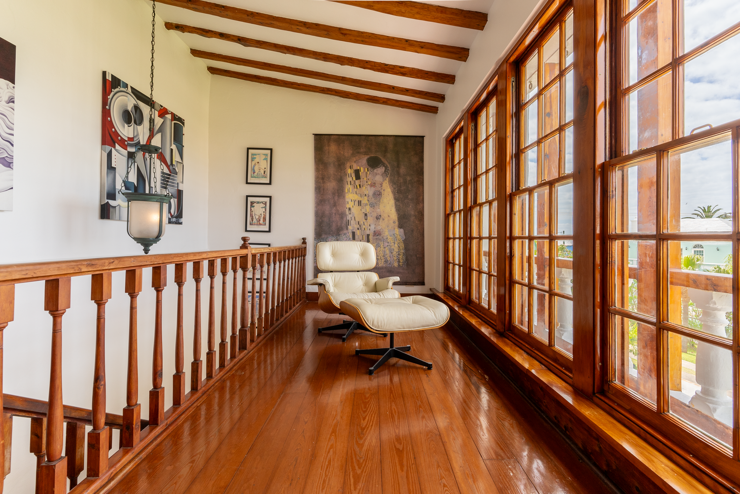 Elegant hallway with wooden beams and large windows offering natural light and coastal views.