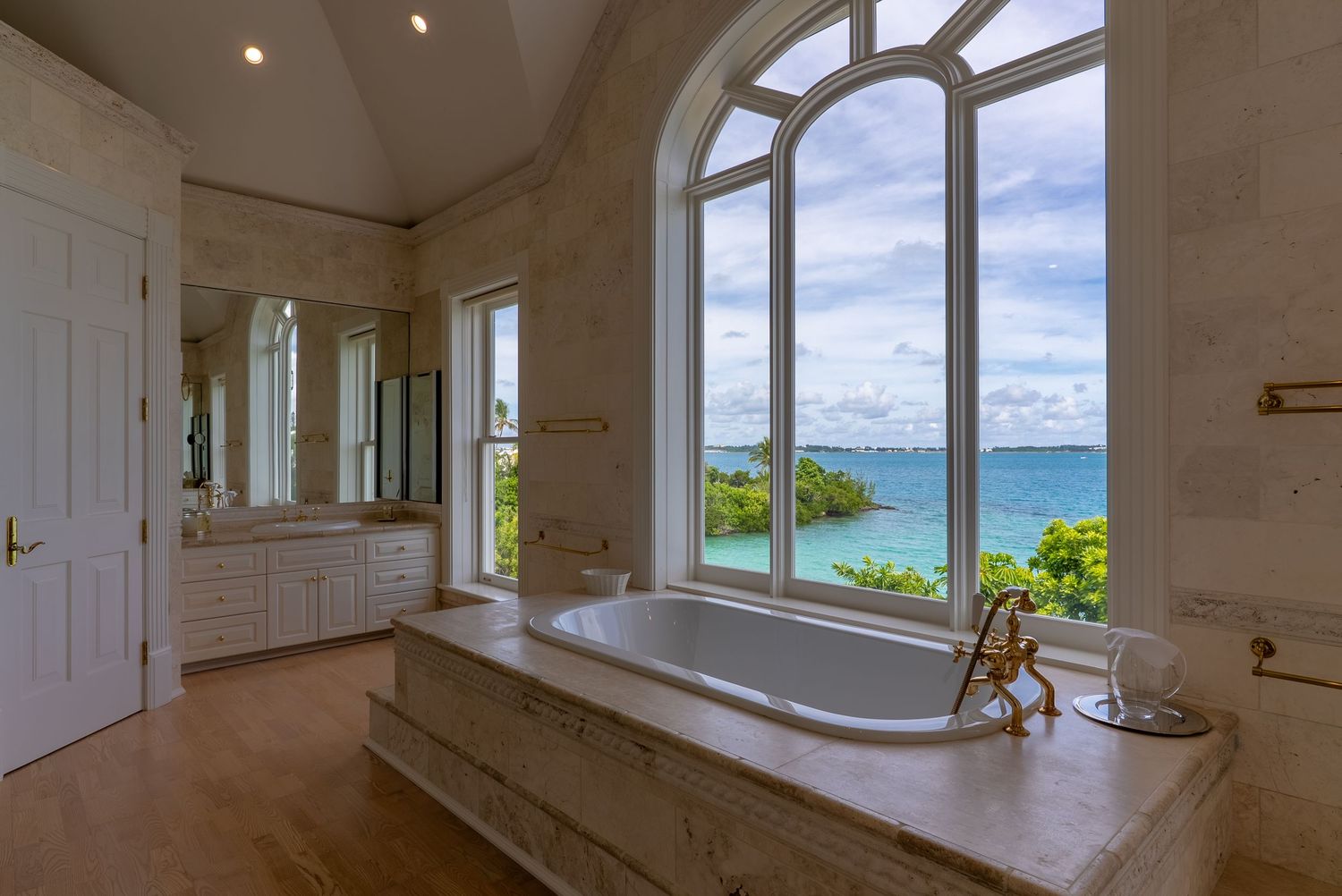 Elegant white interior room with arched windows offering stunning ocean views and natural lighting.