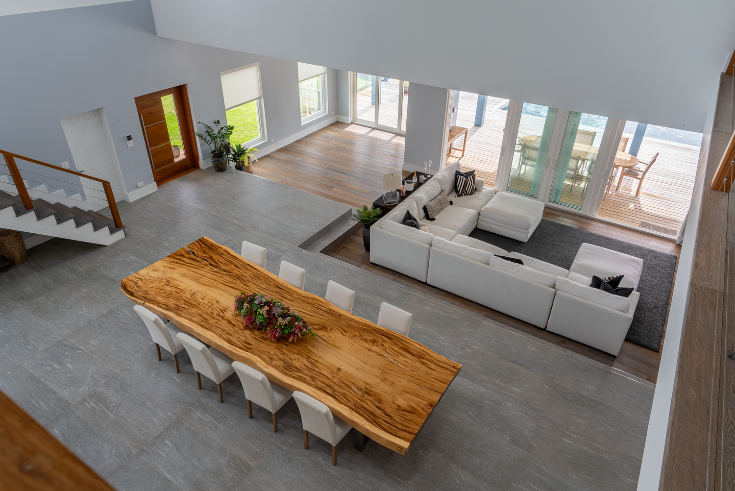 Open floor plan living space with natural wood dining table and modern grey flooring.