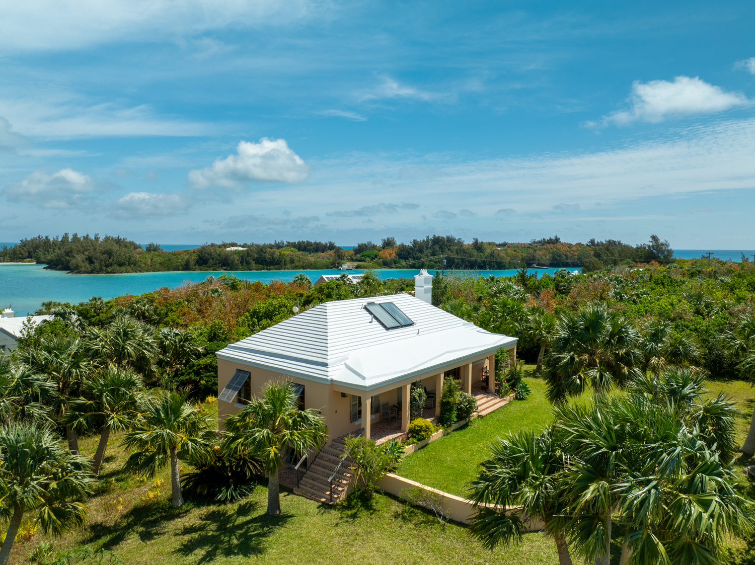 Aerial panorama of luxury waterfront home with lush landscaping and ocean views on a sunny day. Drone photogrpahy.