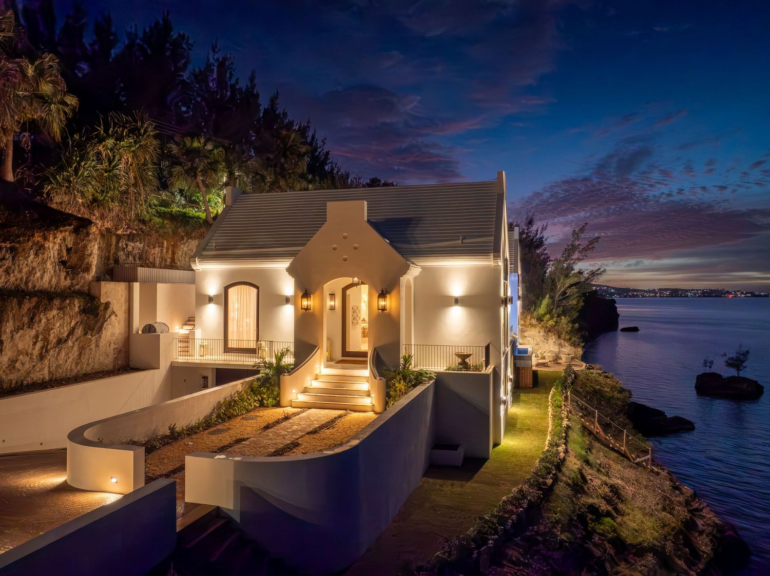 Twilight panorama of an oceanfront luxury residence with dramatic lighting and coastal views. Drone photogrpahy.