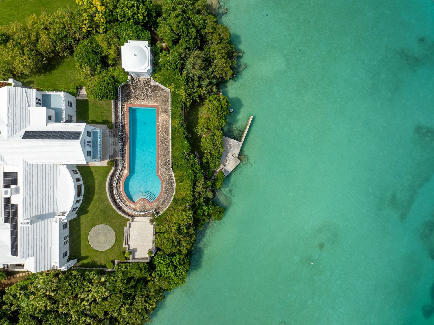 Bird's eye view of luxury waterfront properties with private pools along turquoise coastal waters. Drone photogrpahy.