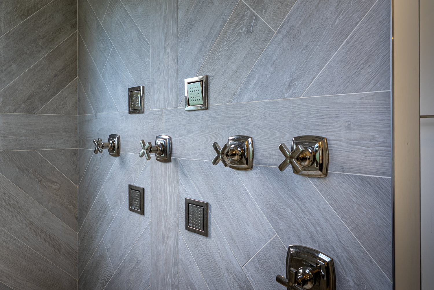 Modern bathroom fixtures and hardware details against grey tile walls.