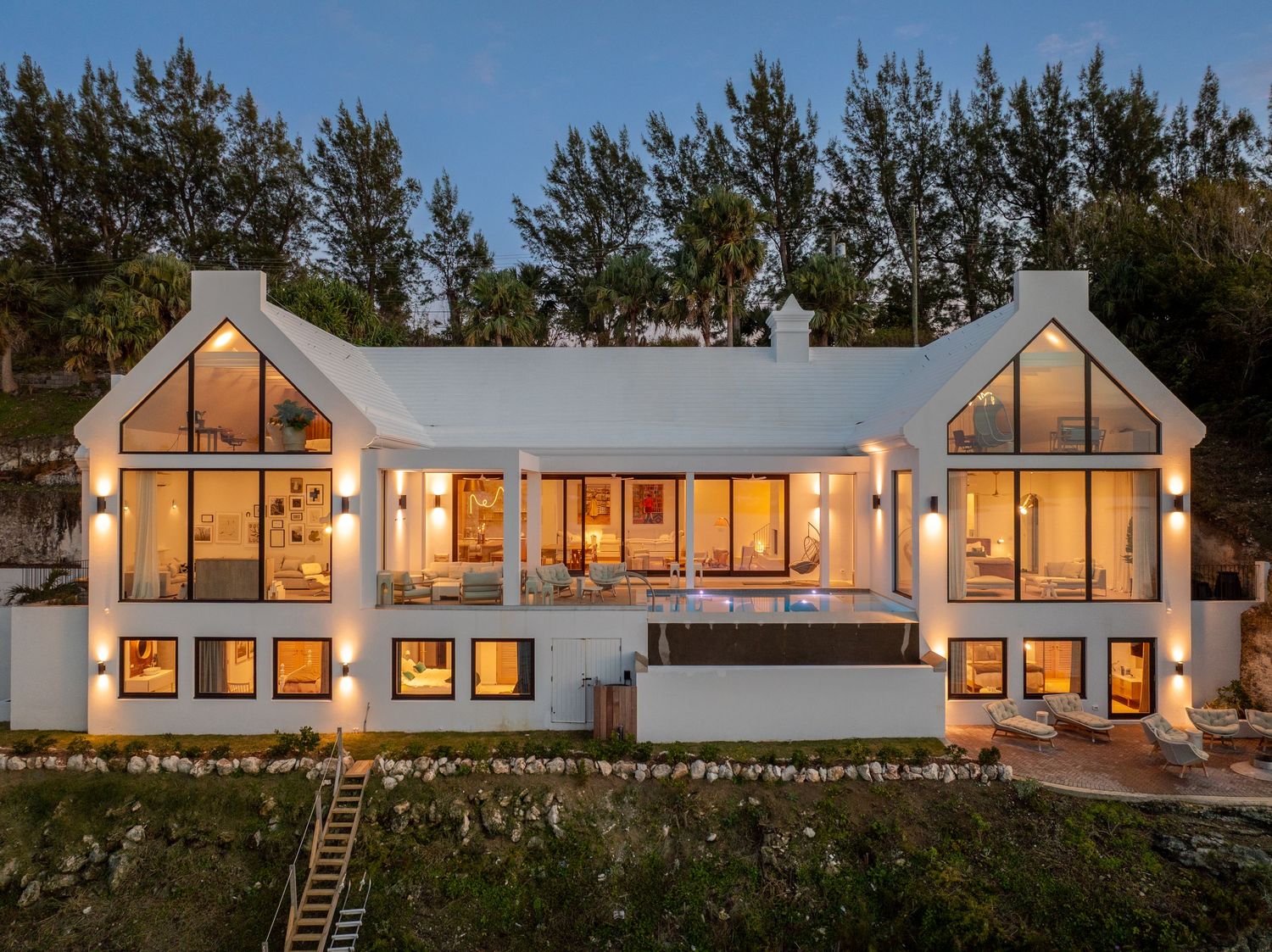 Modern white coastal mansion with large windows and symmetrical architecture at dusk. Drone photogrpahy.