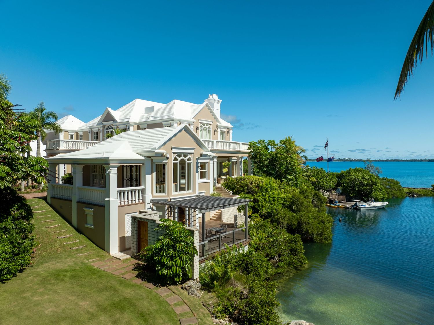 Waterfront property featuring white colonial architecture and manicured lawns along the shoreline. Drone photogrpahy.