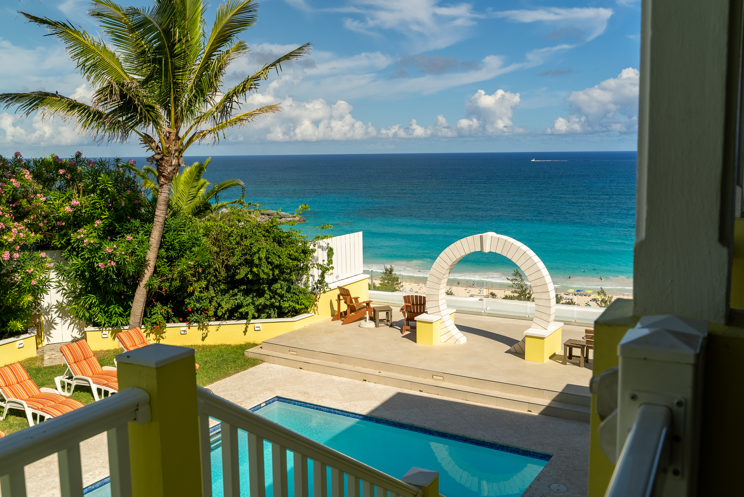 Beachfront villa terrace with swimming pool overlooking turquoise ocean waters.