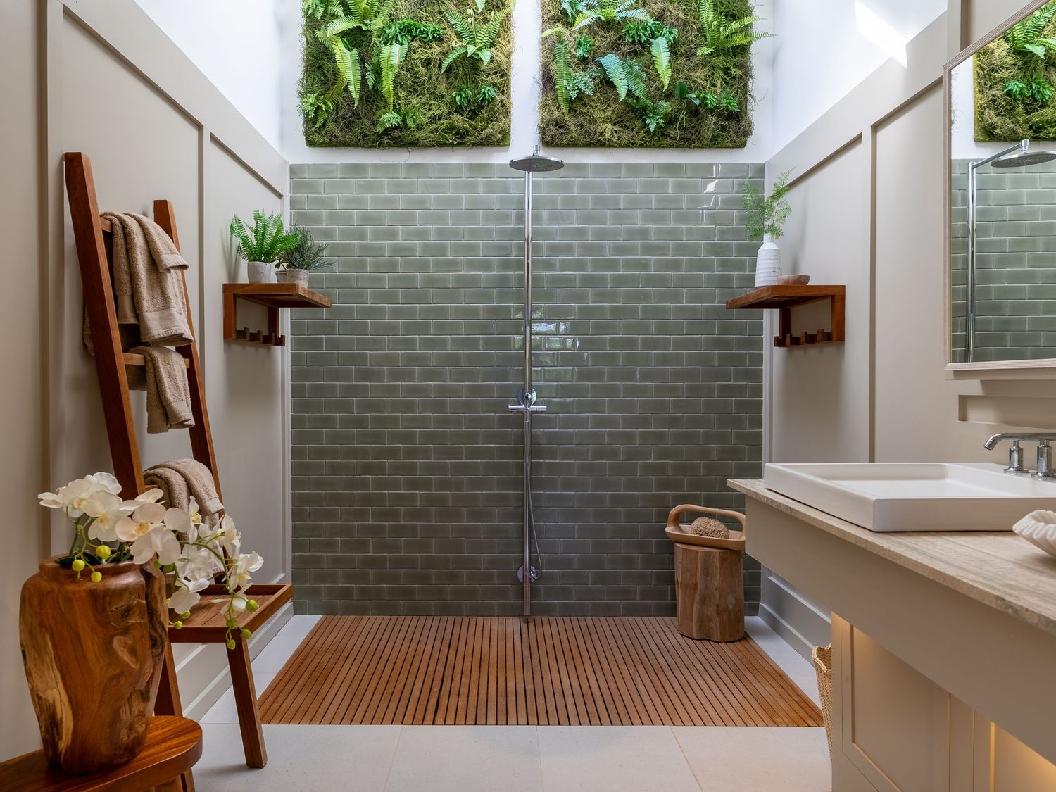 Luxurious bathroom with wooden deck flooring, grey tile walls, and large skylight overhead.
