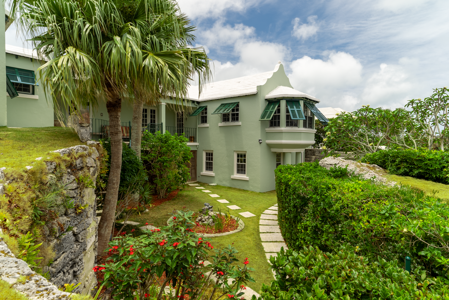 Landscaped garden path winding through tropical vegetation around luxury waterfront property.