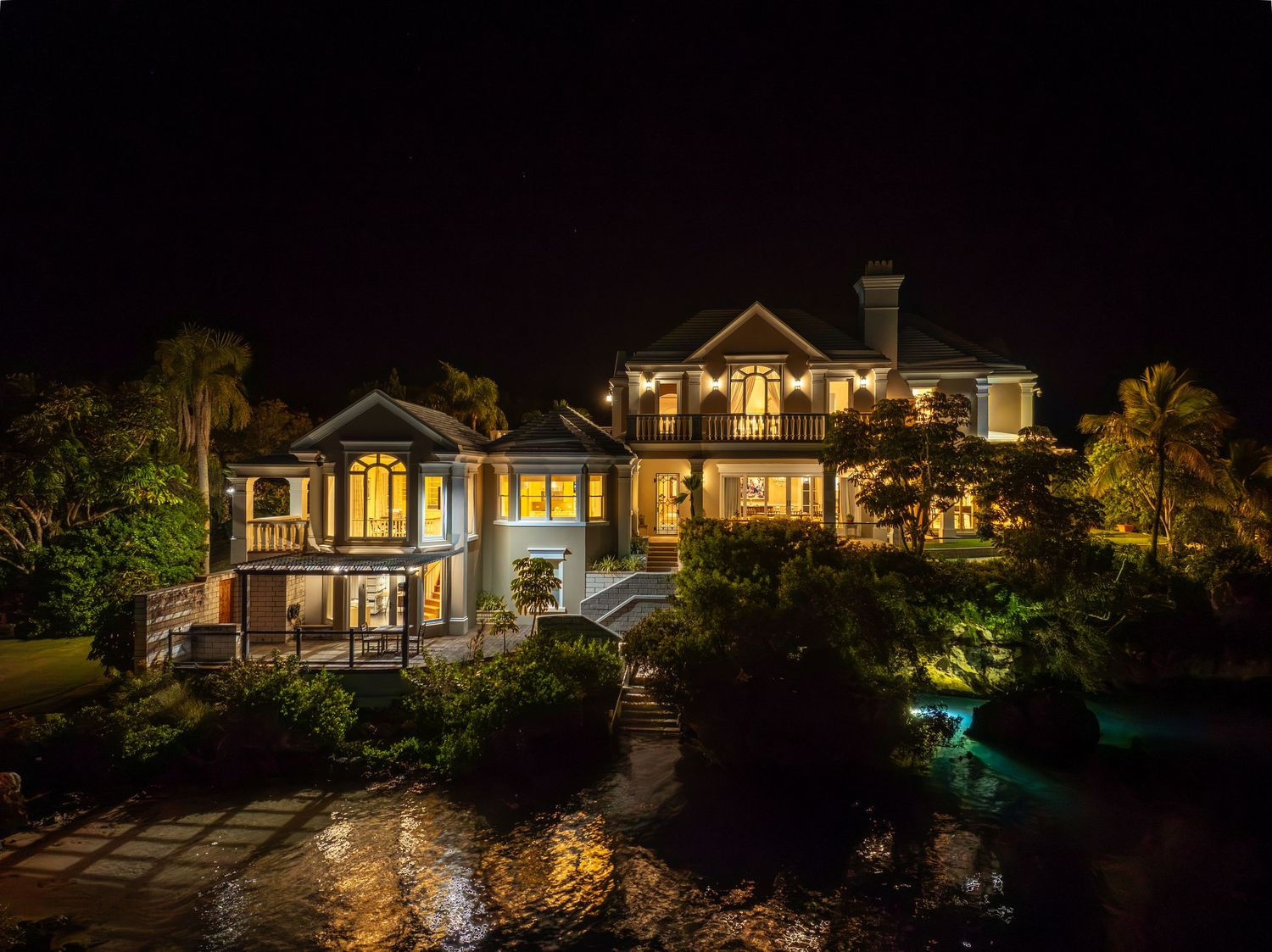 Panoramic view of a coastal luxury home with dramatic evening lighting and landscaping. Drone photogrpahy.