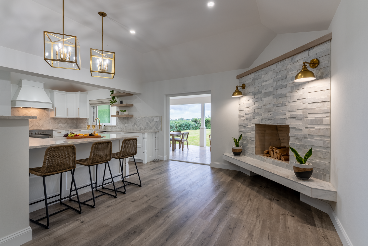 Modern open concept living space with light wood floors, white walls, and contemporary pendant lighting fixtures.