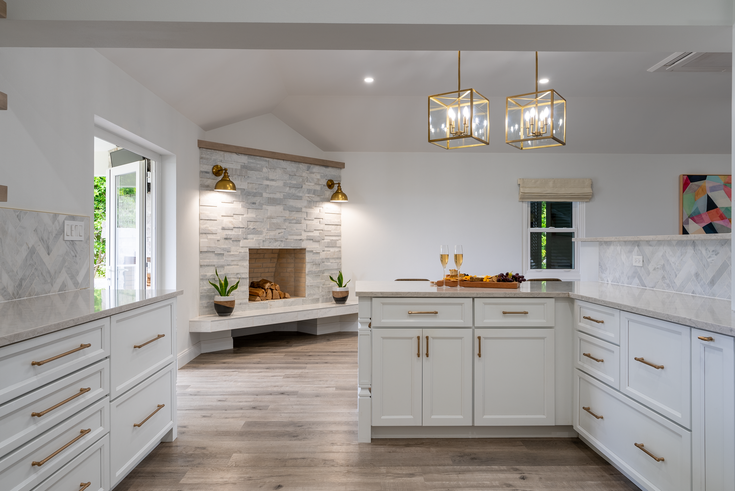 Luxurious white kitchen featuring marble countertops, gold hardware, and modern appliances in an open layout.
