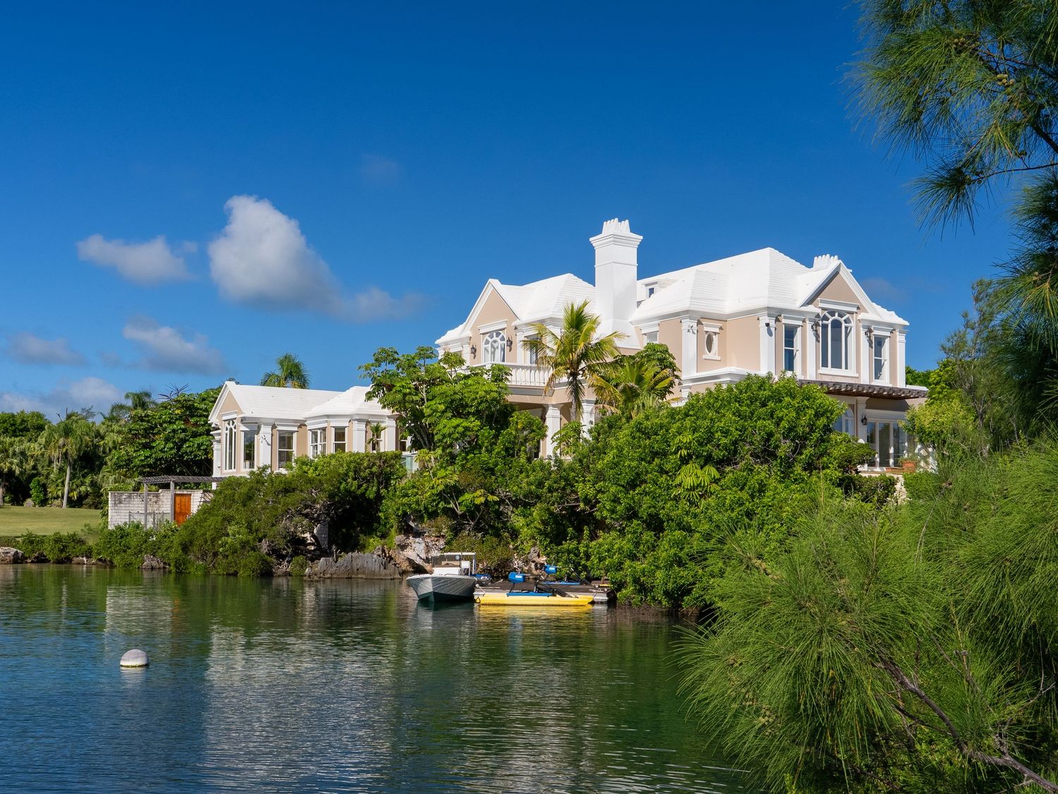 Row of luxury waterfront homes with private docks and lush tropical gardens.