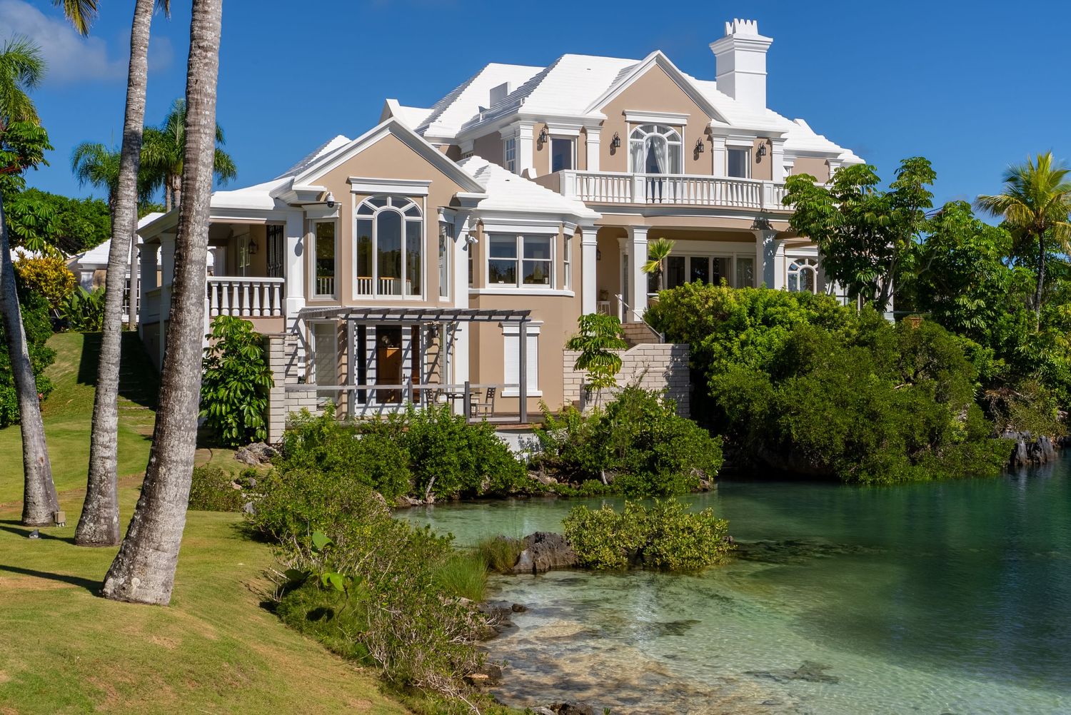 Elegant waterfront mansions with classic architecture along a tranquil lagoon.