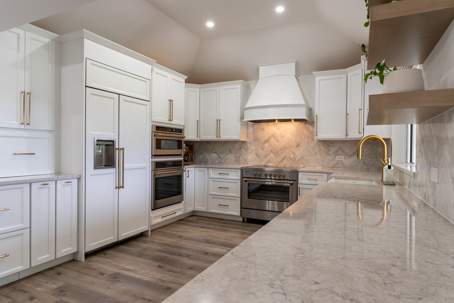 Expansive white kitchen with marble backsplash, custom cabinetry, and stainless steel appliances.