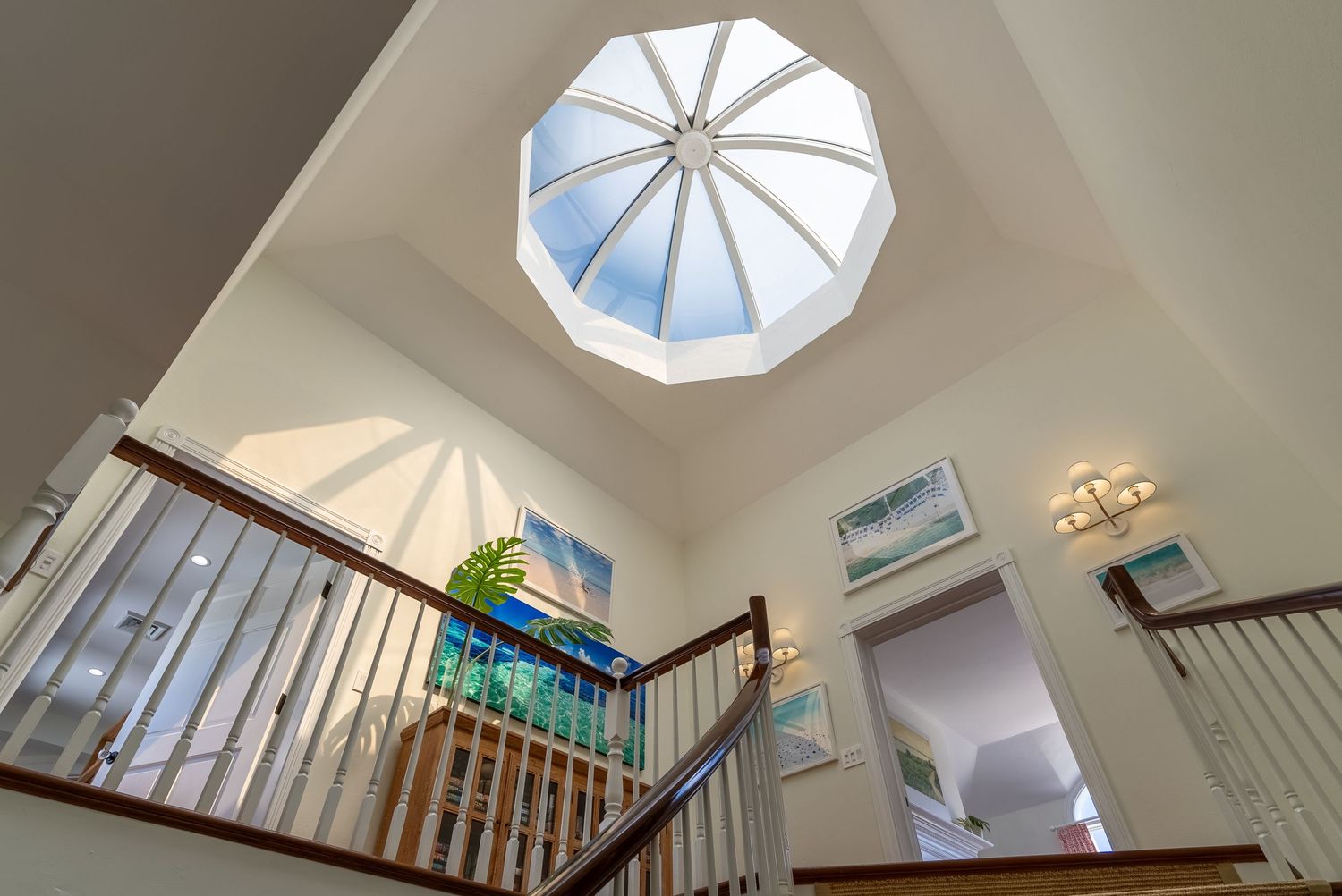Elegant staircase with skylights illuminating a bright white interior space with wooden railings and natural light.
