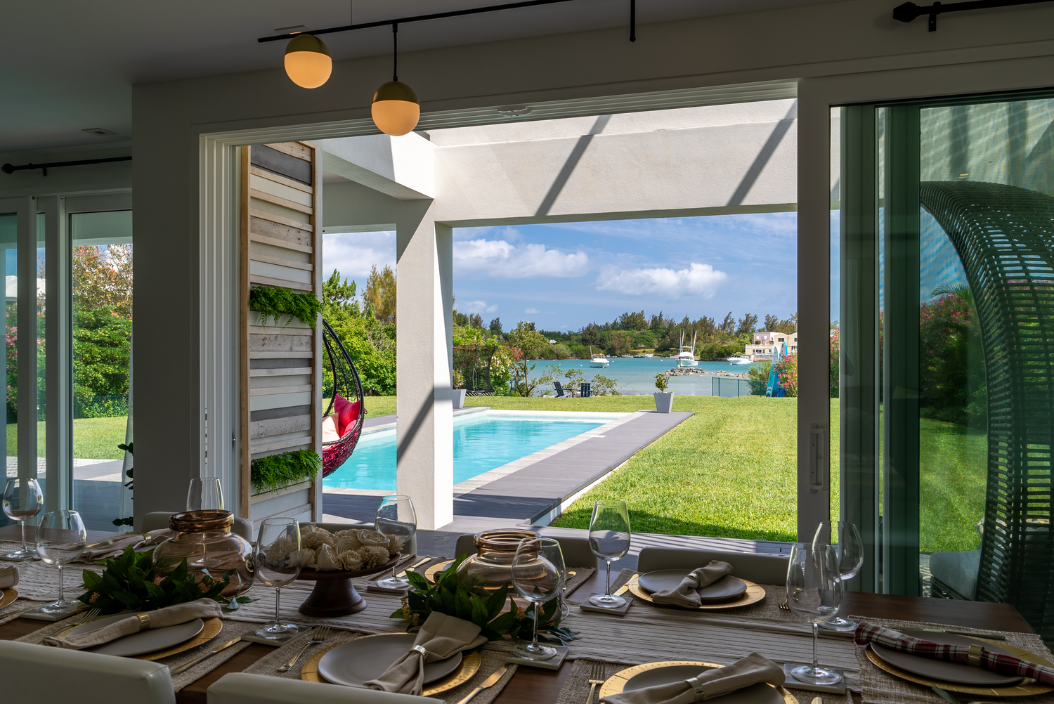Waterfront living room with floor-to-ceiling windows offering stunning pool and ocean views.