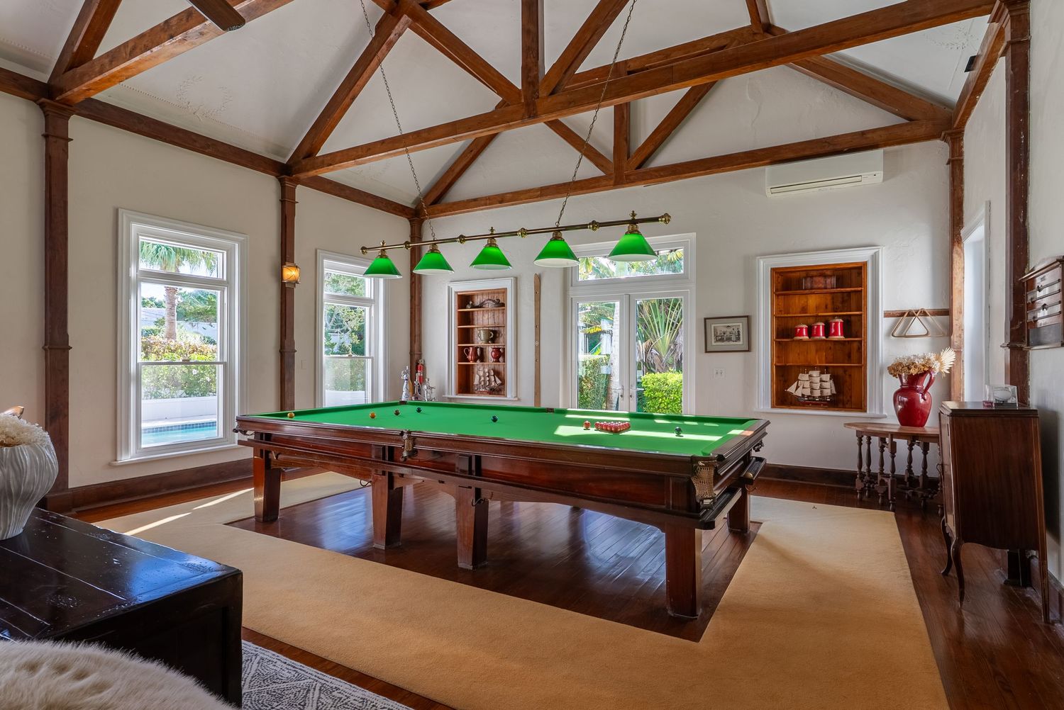 Spacious game room with exposed wooden beams featuring pool tables and entertainment area.