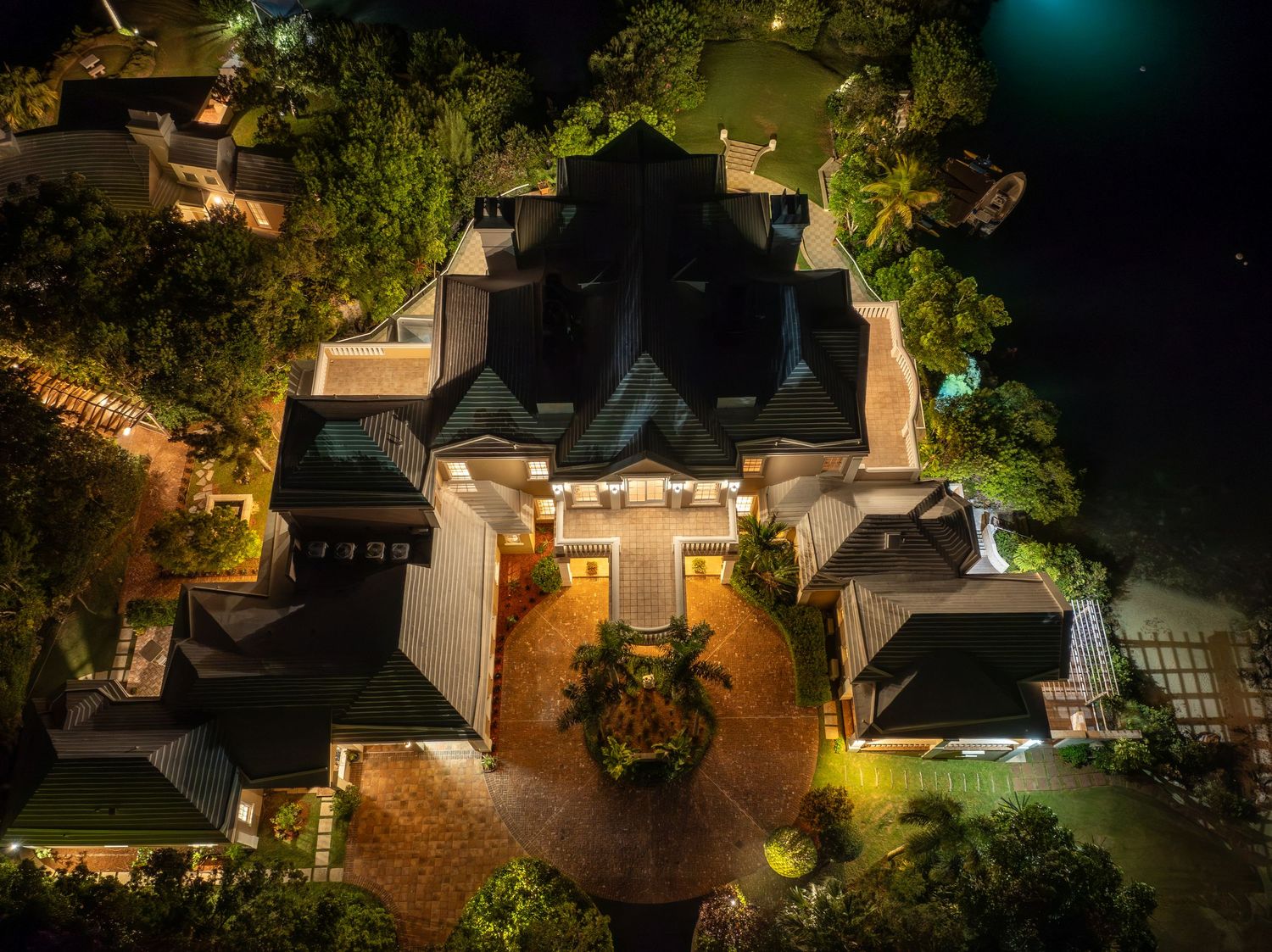 Aerial view of an expansive estate with warm lighting and manicured grounds after dark. Drone photogrpahy.