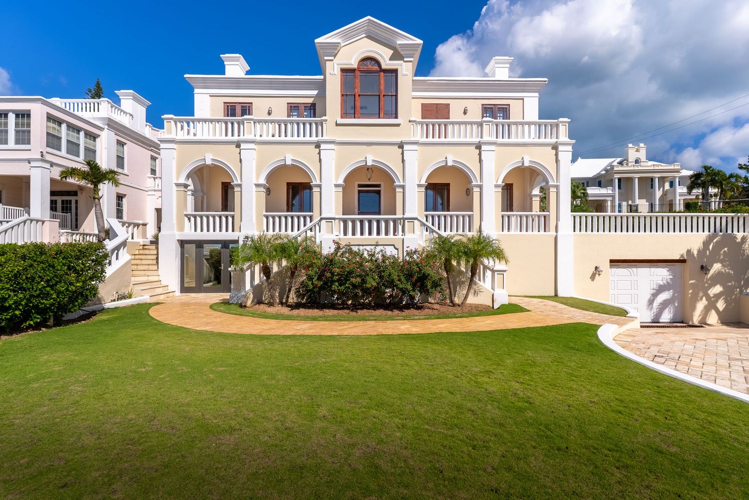 Expansive white colonial-style mansion with arched windows and manicured grounds.