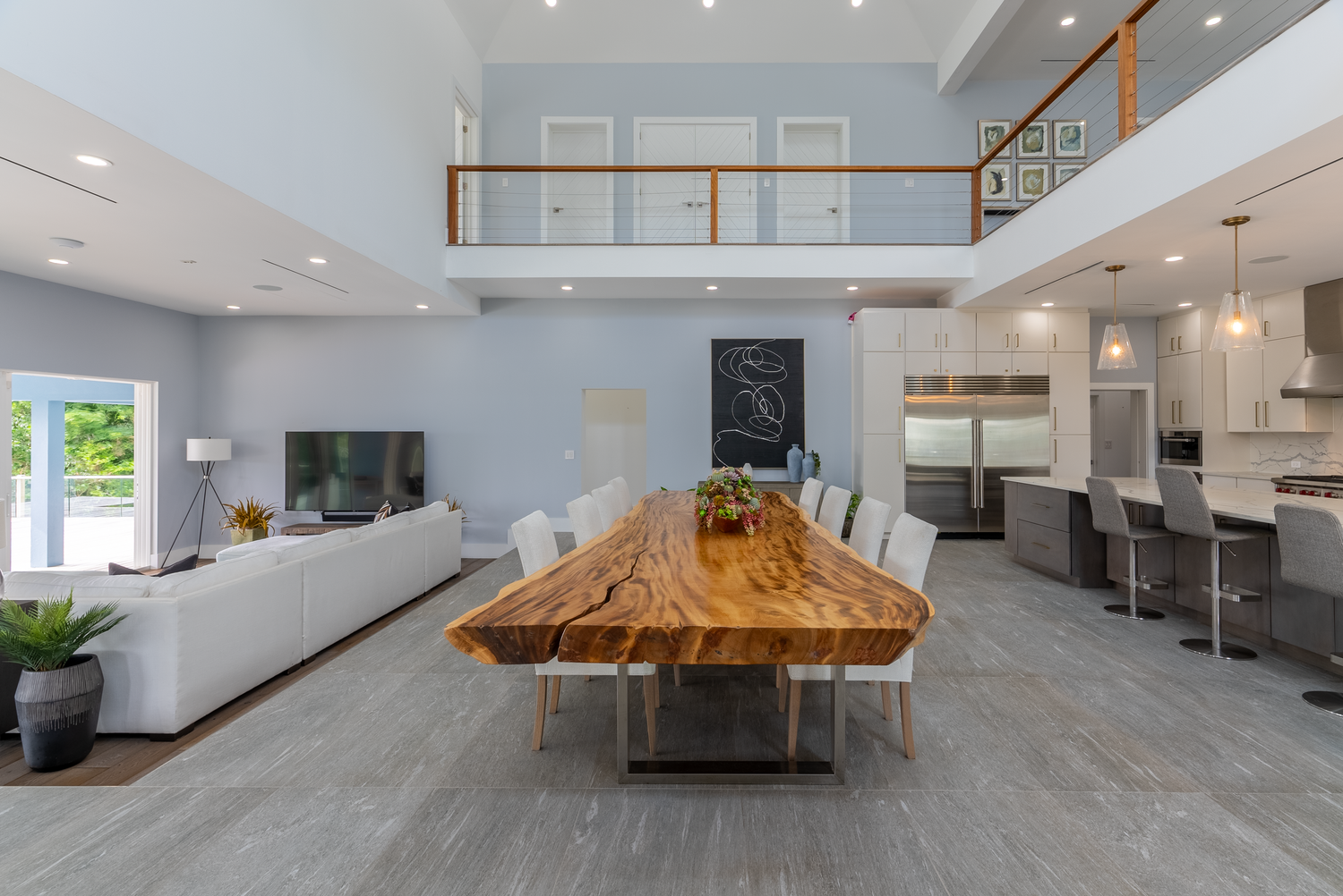 Contemporary great room featuring high ceilings, live-edge wood table, and minimalist design elements.