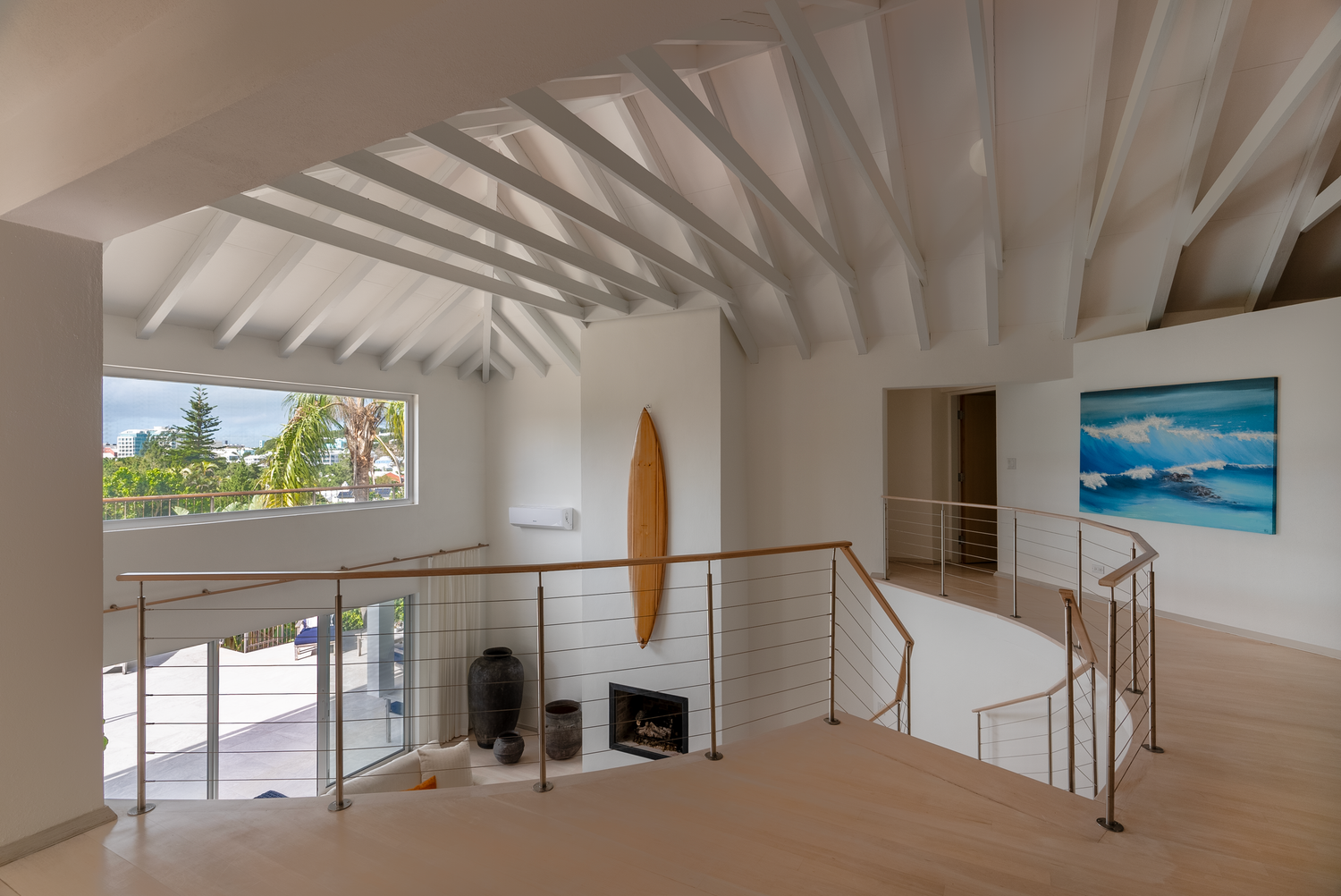 Open concept living space with white beamed ceilings and contemporary furnishings.