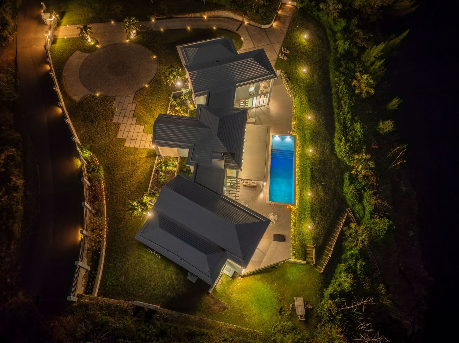 Drone shot of an elegant mansion with swimming pool and garden lighting at night. Drone photogrpahy.