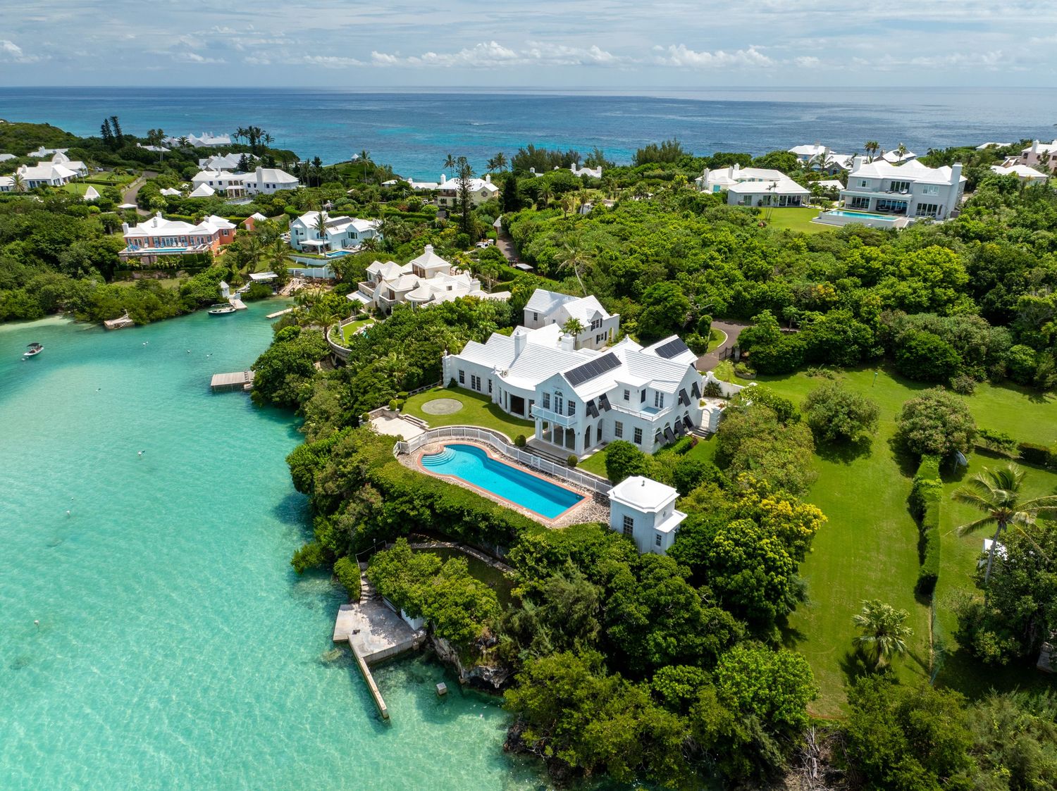 Aerial view of luxury waterfront estates with white roofs nestled among tropical greenery. Drone photogrpahy.