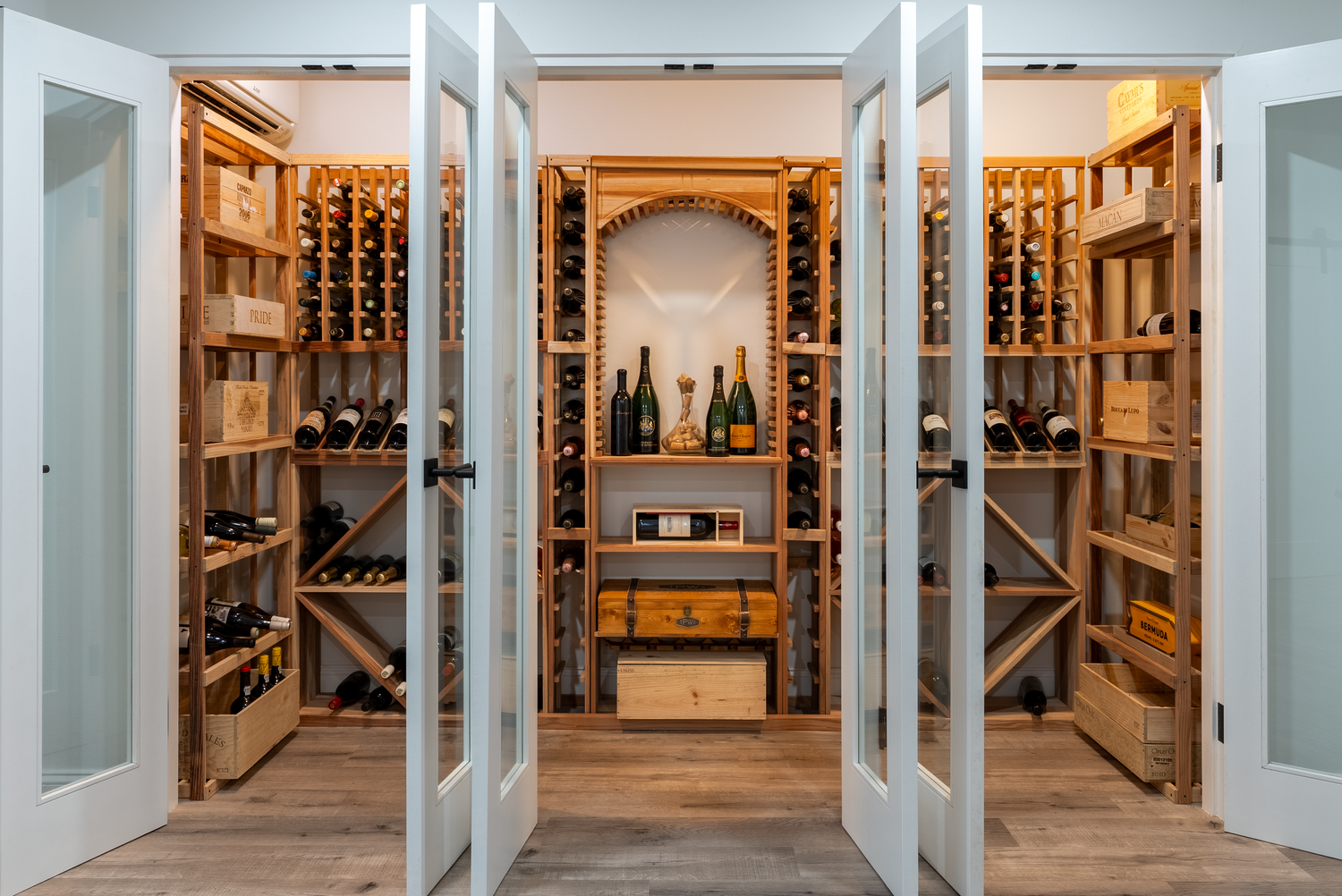 Custom wood wine cellar with glass doors and built-in storage displays illuminated by warm lighting.