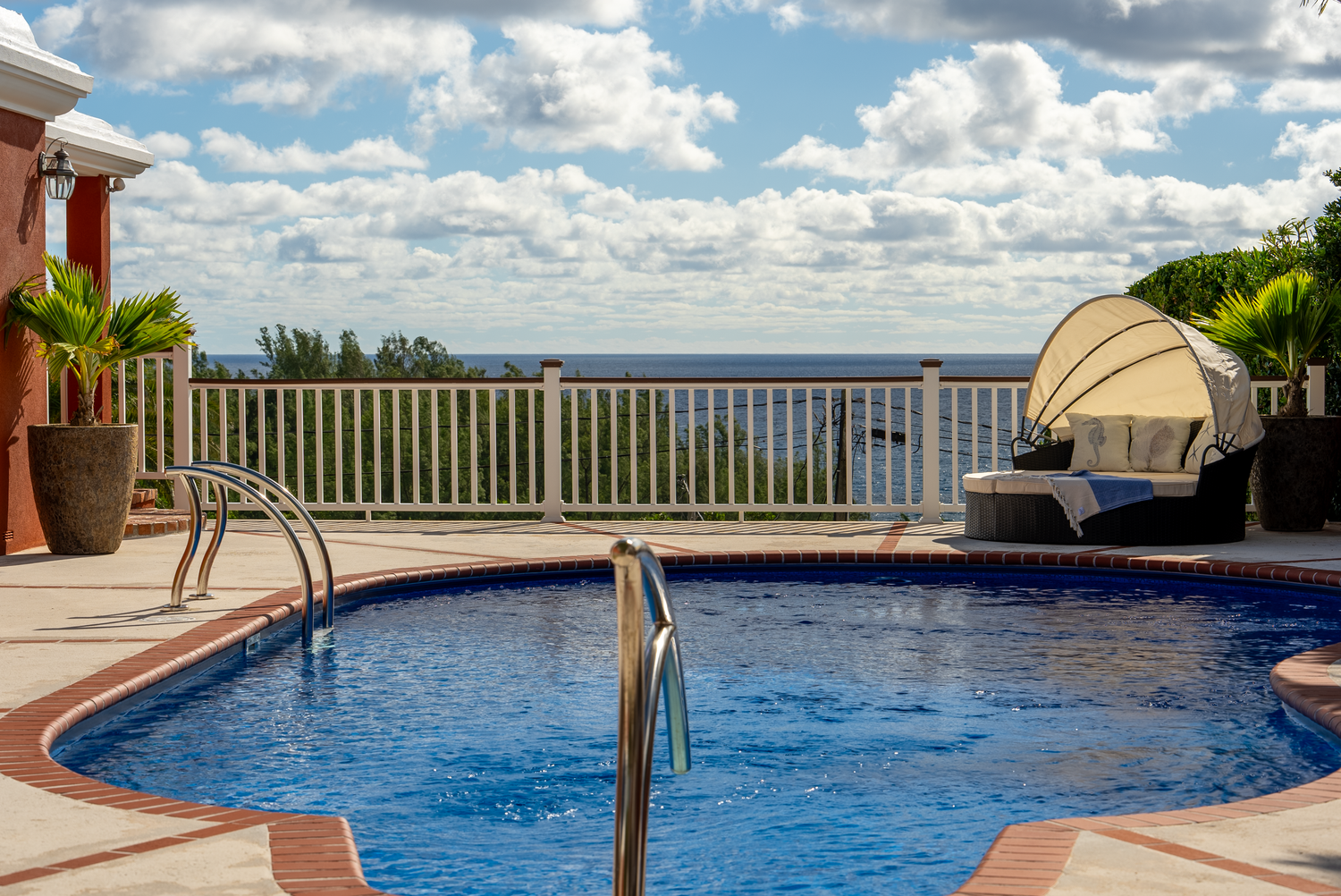 Curved infinity pool with ocean views and modern lounging areas under blue skies.