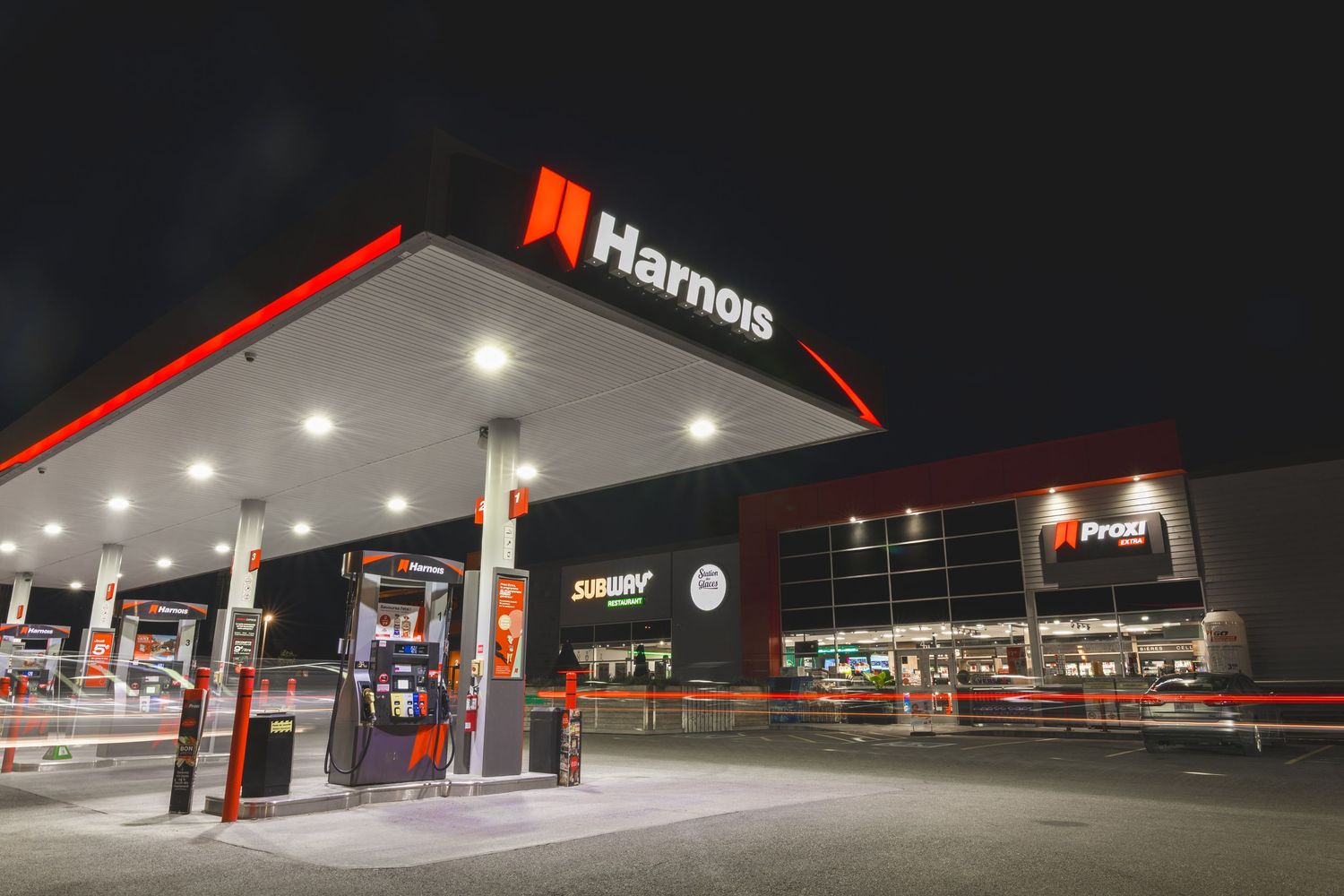 A series of gas stations at night showing illuminated red and white Harnois fuel station canopies and storefronts.