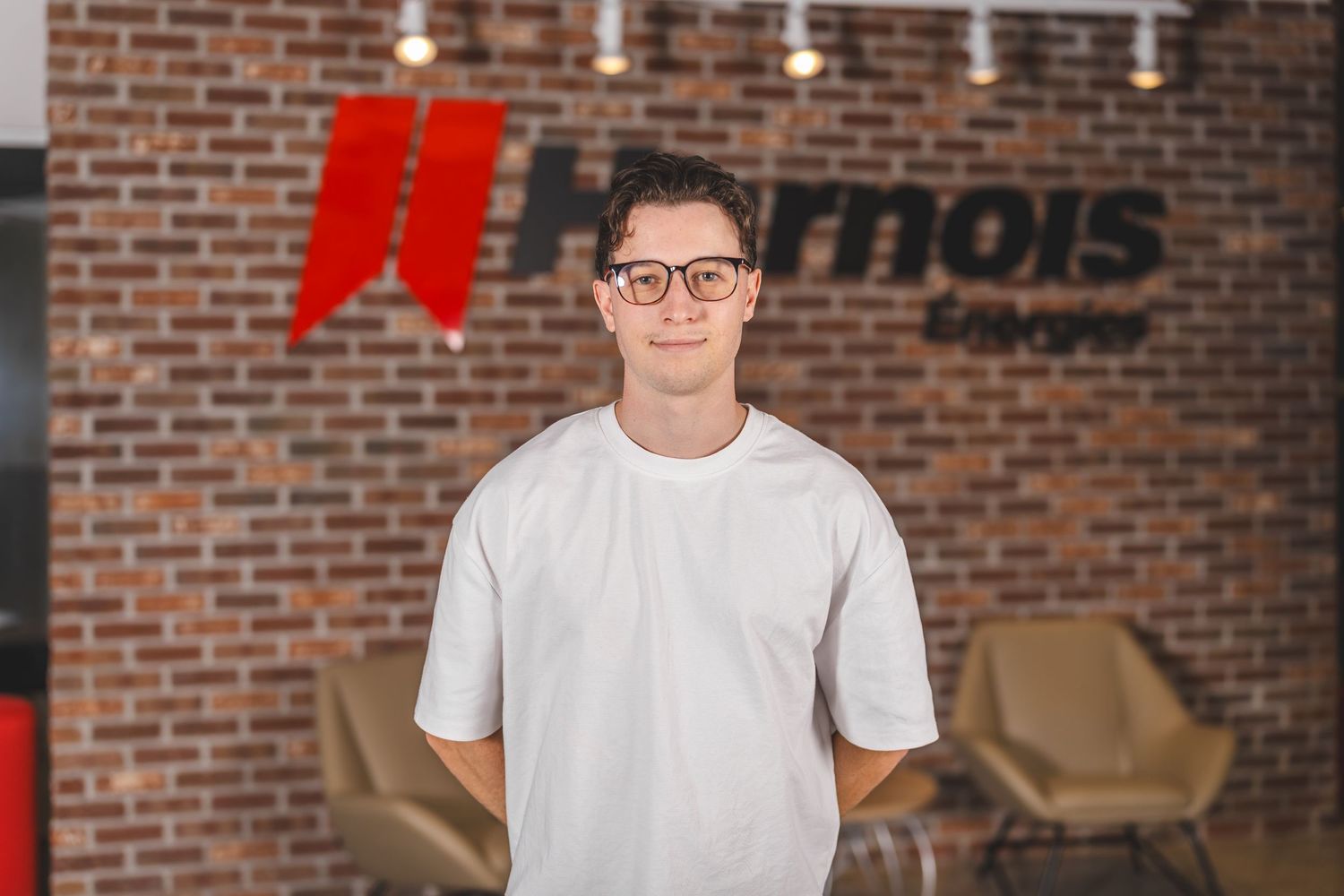 Professional portrait against exposed brick wall with company branding visible.