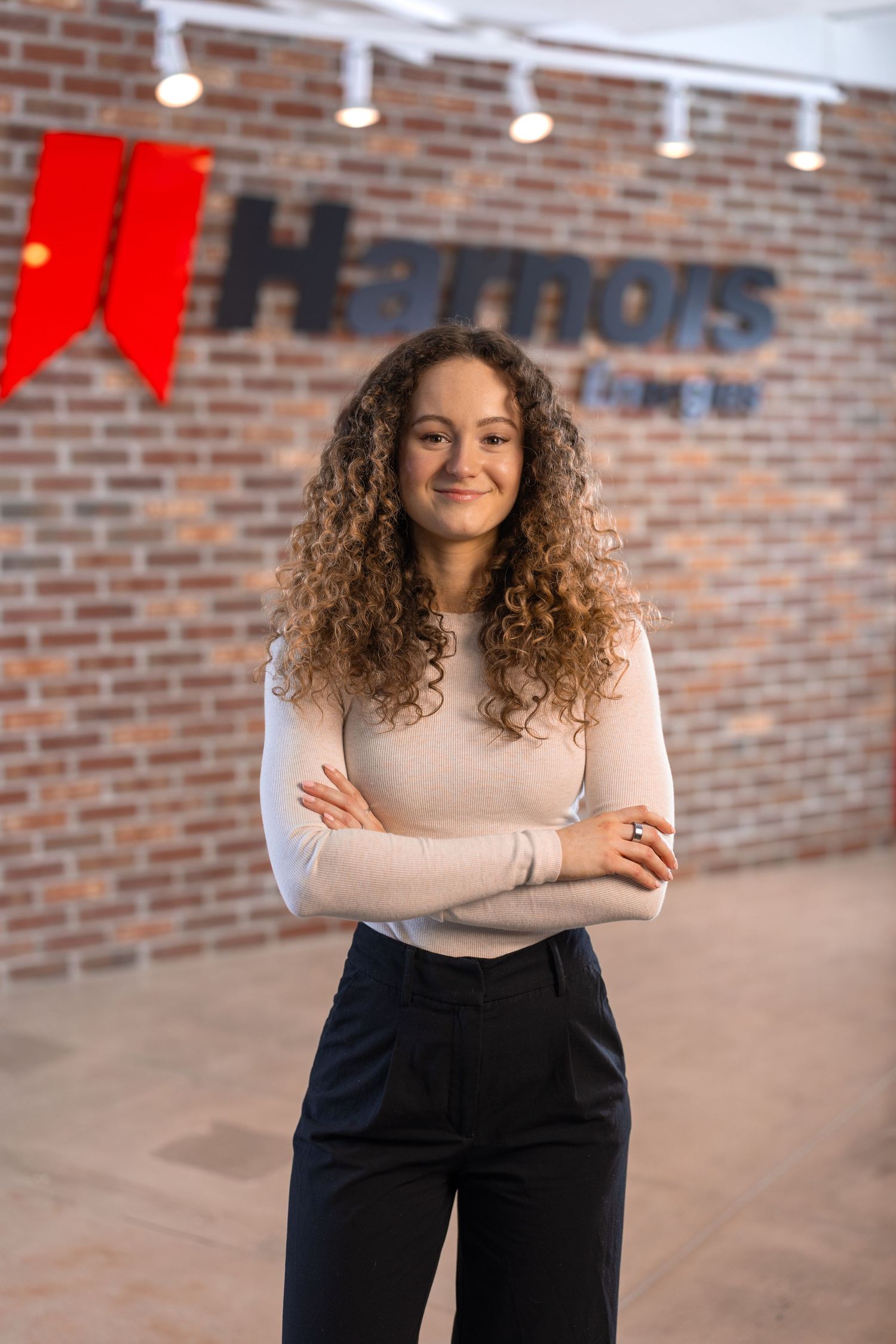 Professional portrait against brick wall with red company branding visible.