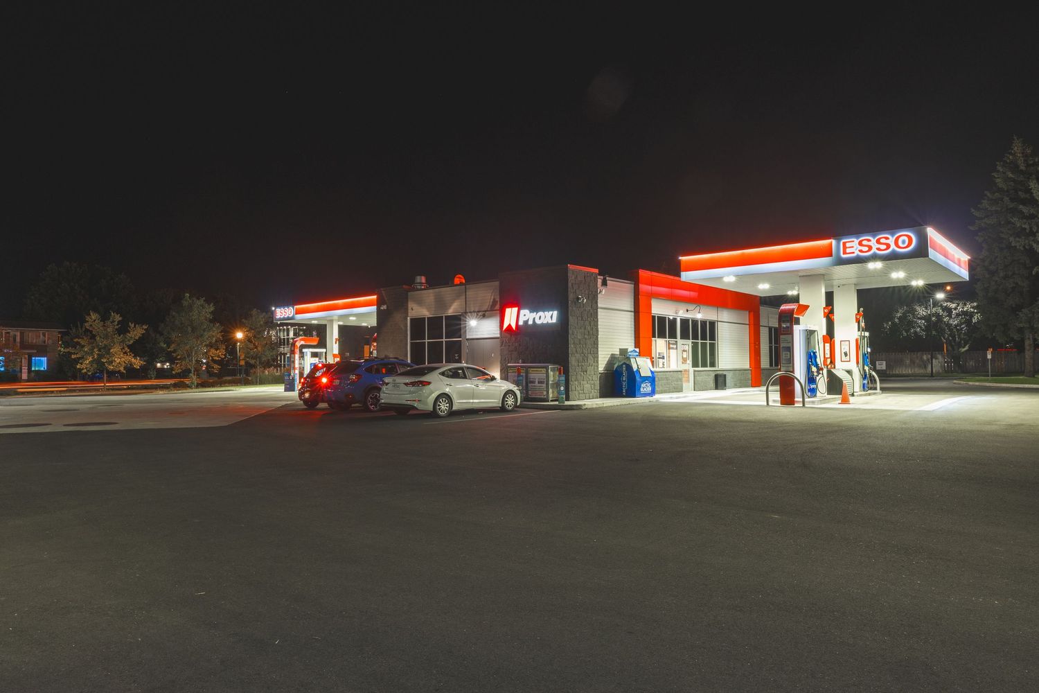 A gas station convenience store illuminated at night with bright lights and red accents on the exterior.