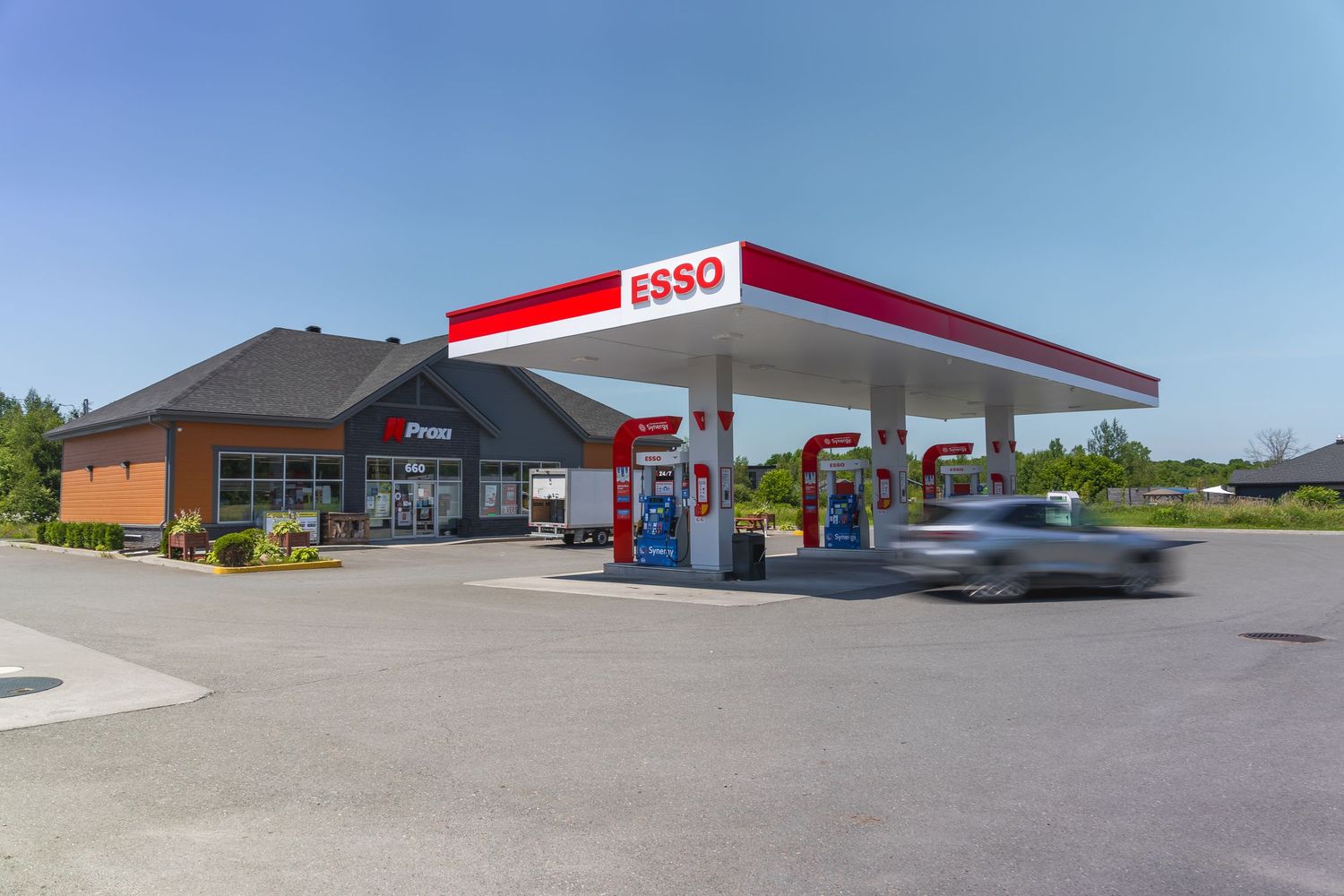 A series of Esso gas station buildings and fuel pumps shown from different exterior angles during daytime.