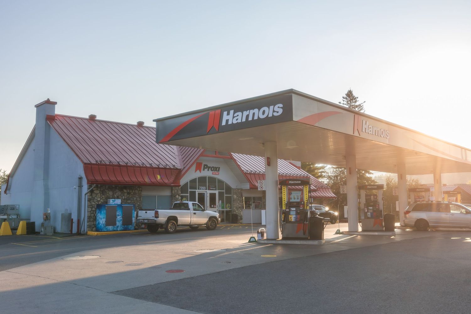 Harmons gas station exterior with red roof and fuel pumps during golden hour sunset.