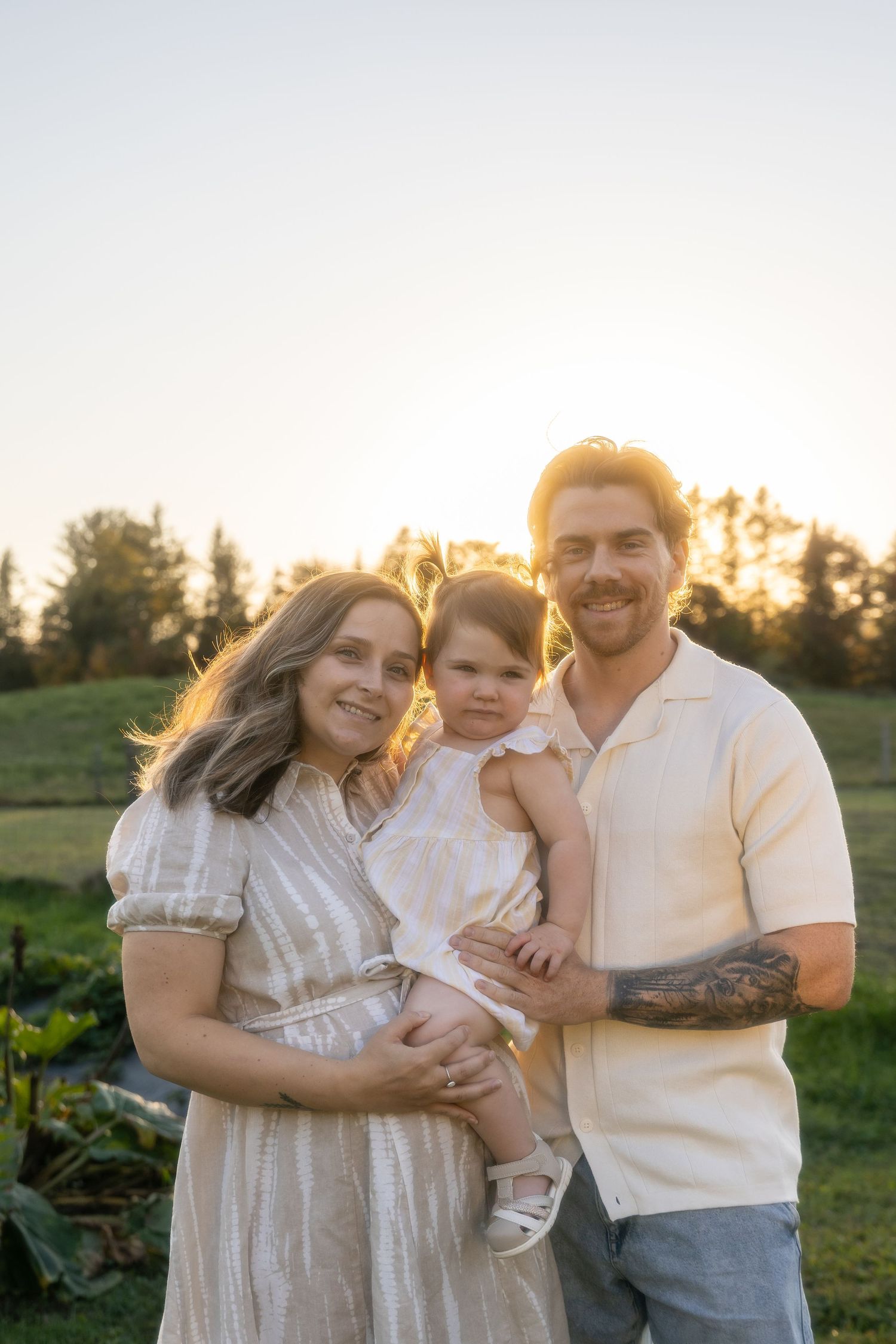 Family portrait in field during golden hour with sunset lighting.