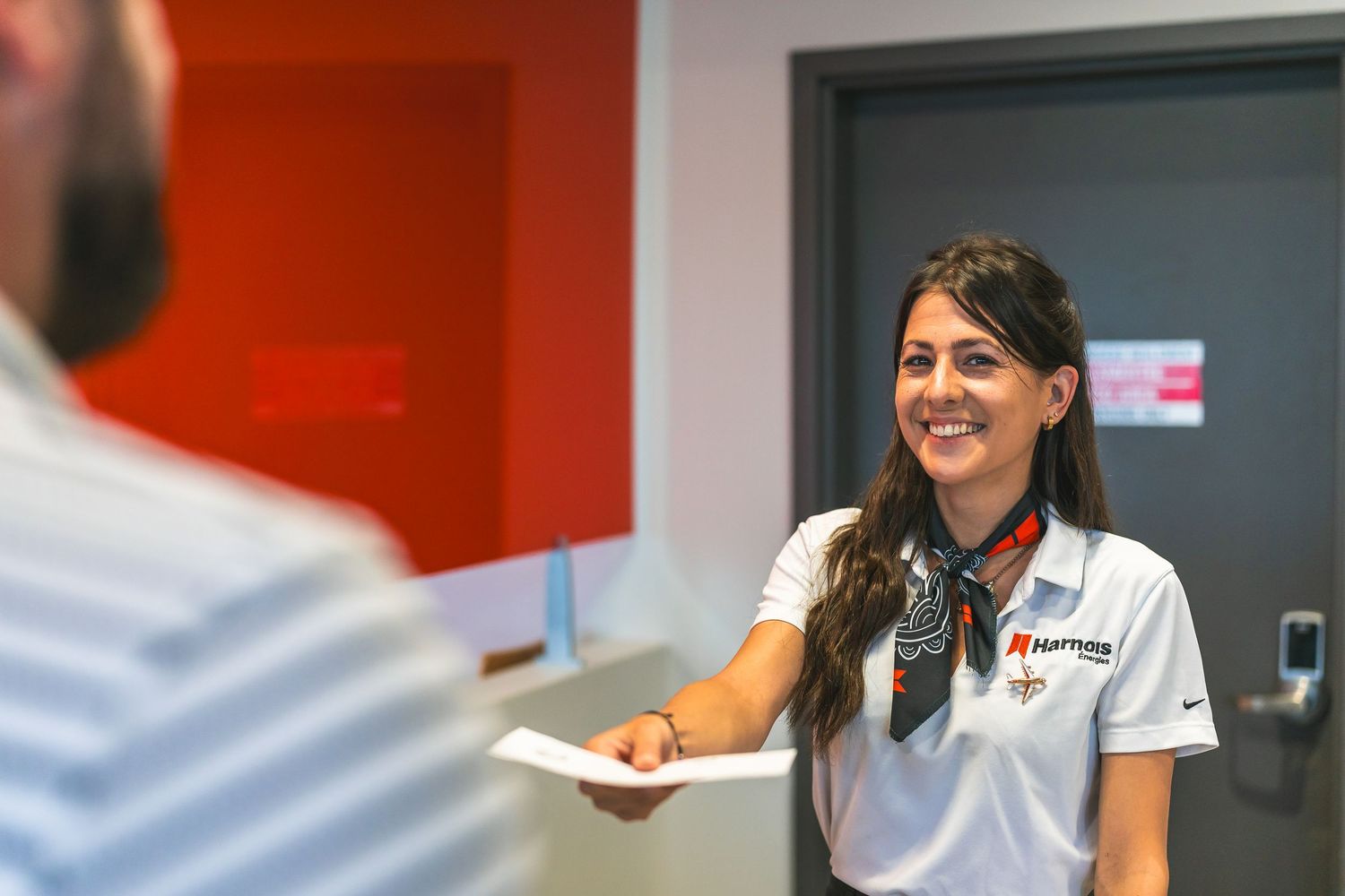 Staff member in dark uniform engaging in conversation in office setting.