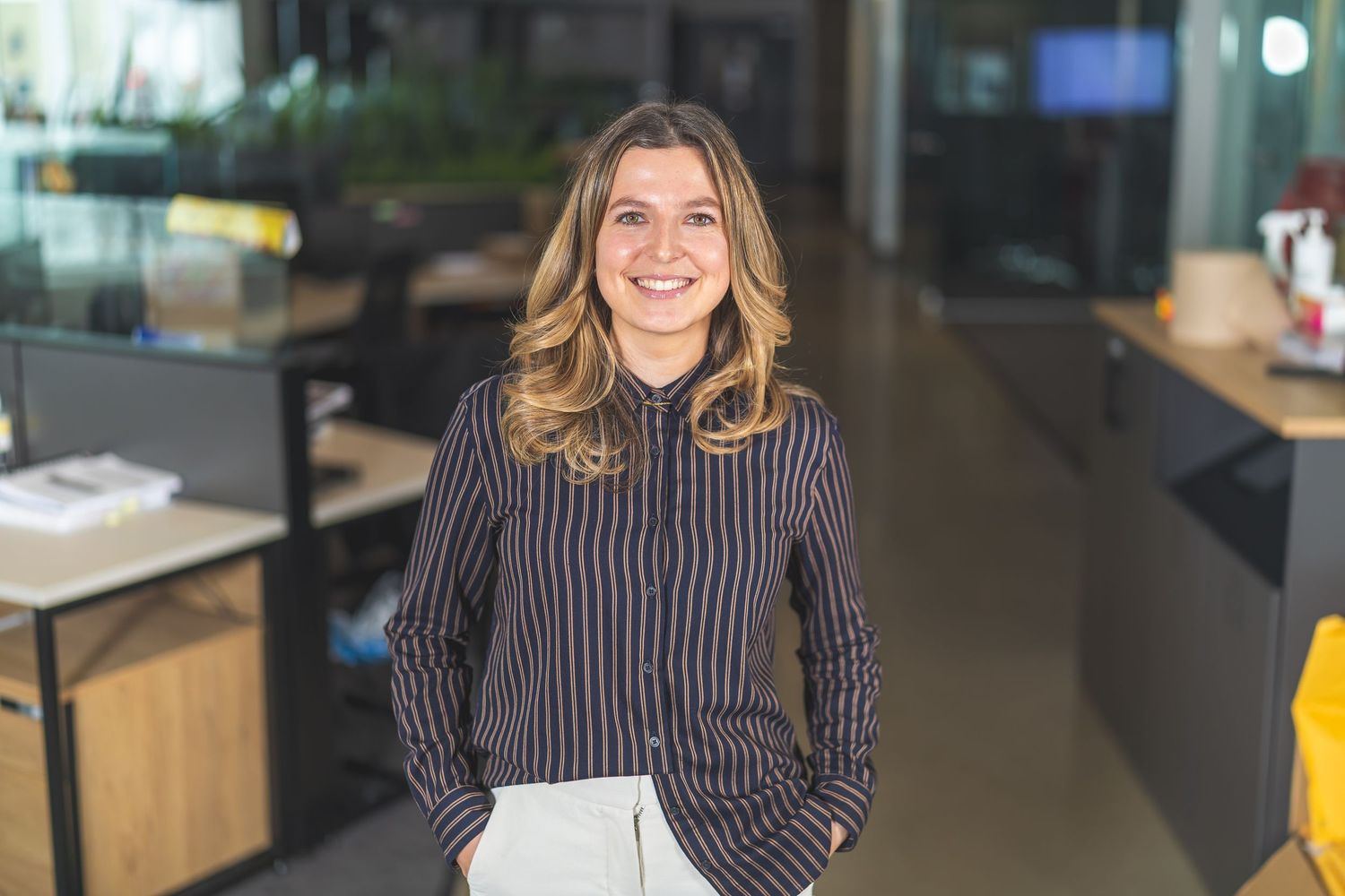 Professional portrait in striped attire against modern office background.