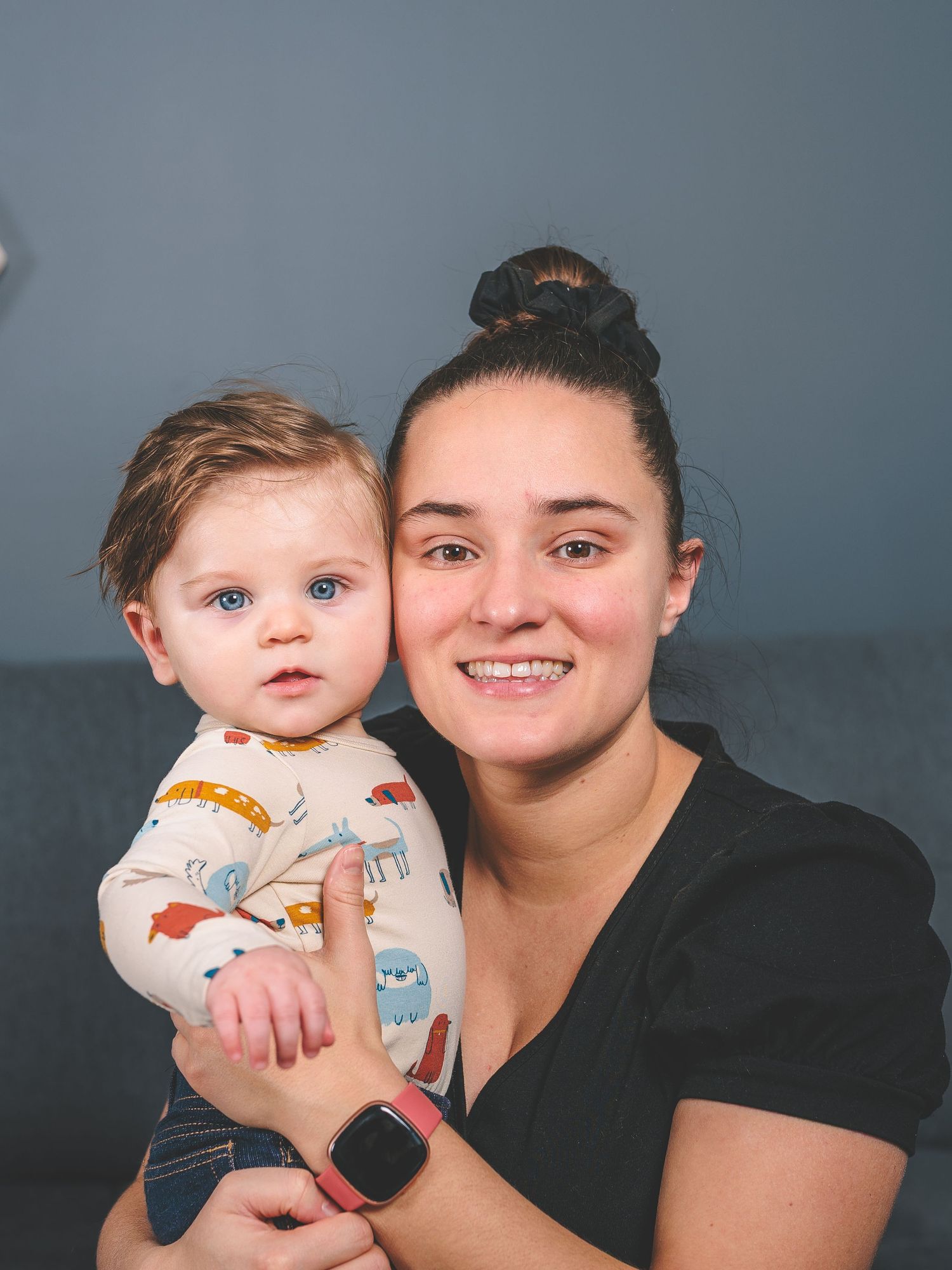 Studio portrait against blue backdrop shows loving parent-child moment.
