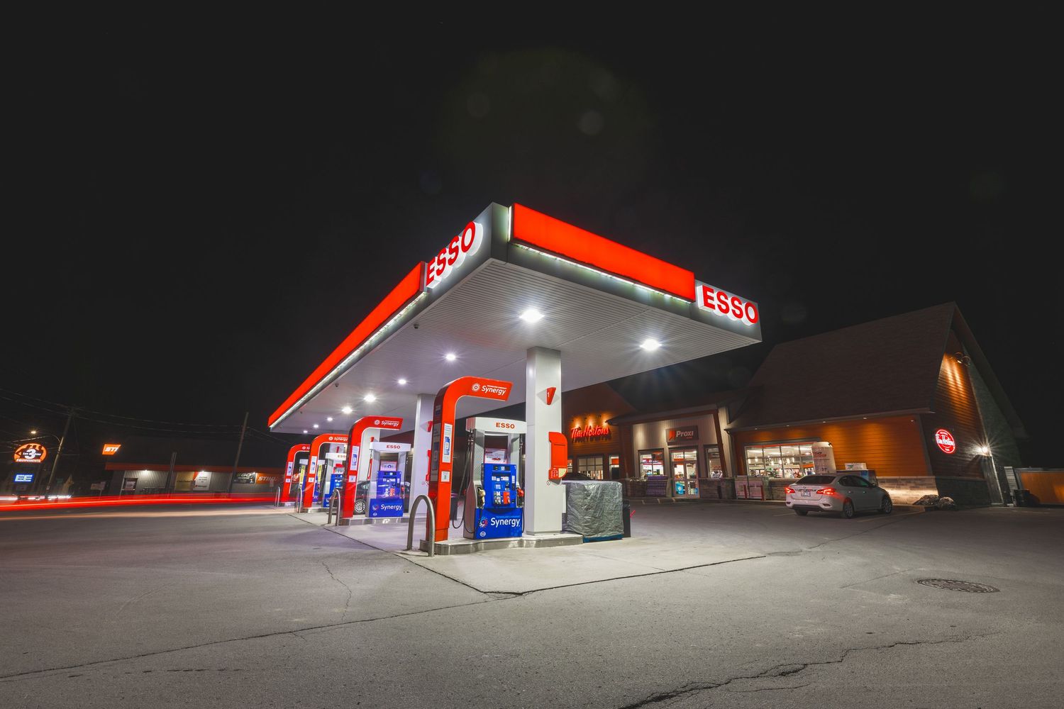 Esso gas station illuminated at night with red and white signage glowing against the dark sky.