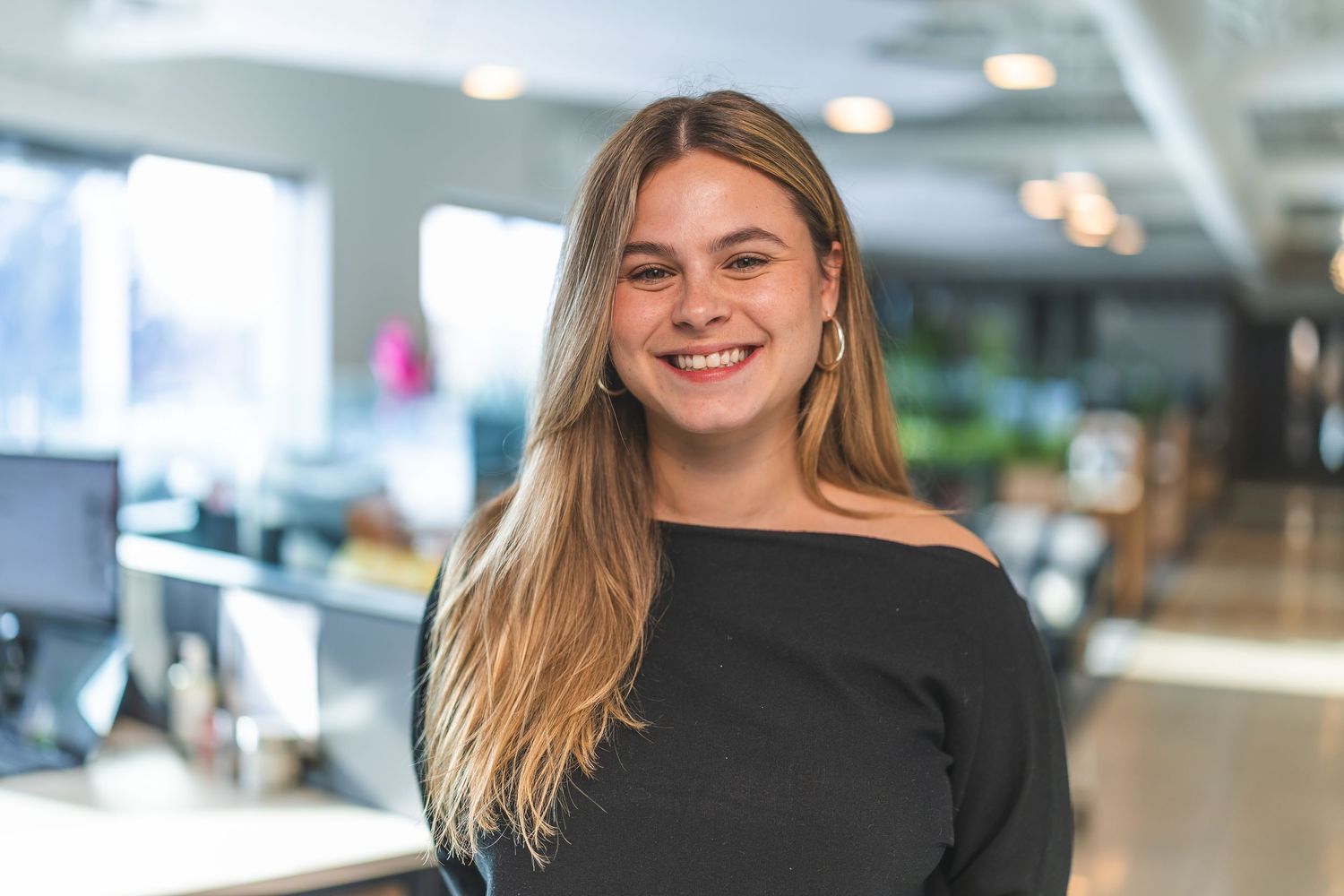 Professional wearing black top in bright corporate office setting.