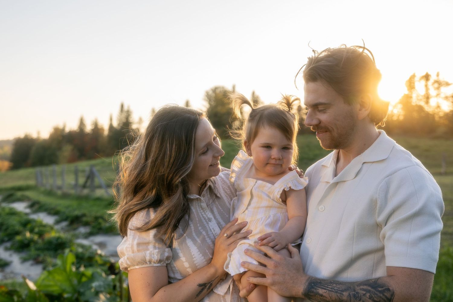 Family sharing tender moment together in field at sunset.
