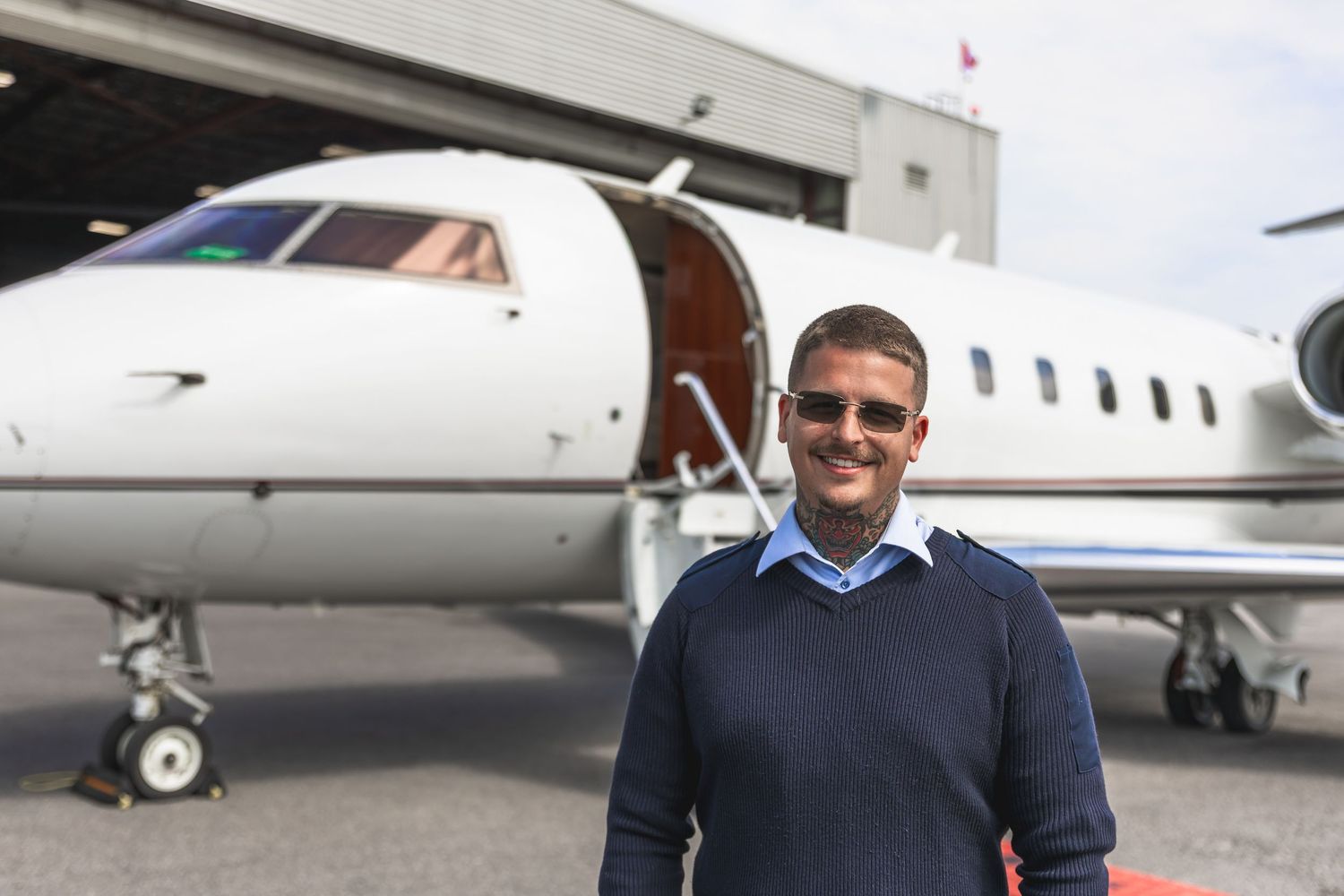 Business professional standing near private aircraft on airport tarmac.