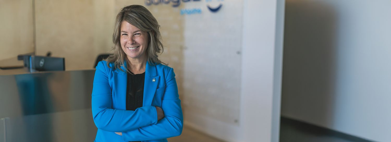 Person in bright blue jacket standing against white wall.
