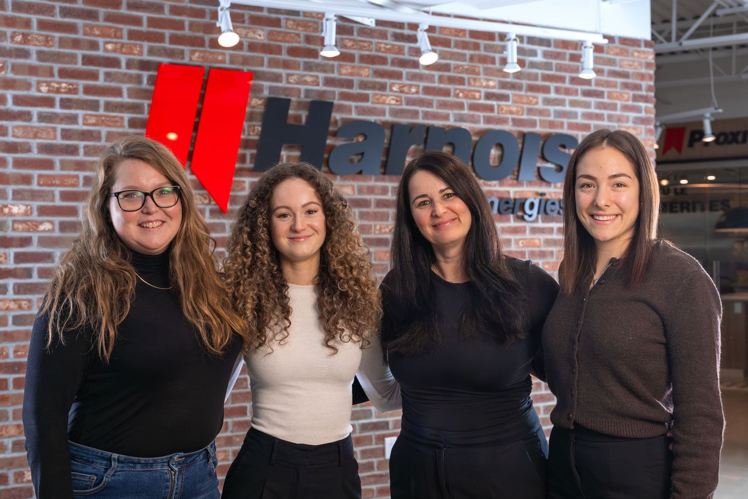 Group of team members smiling in modern office setting with exposed brick wall.