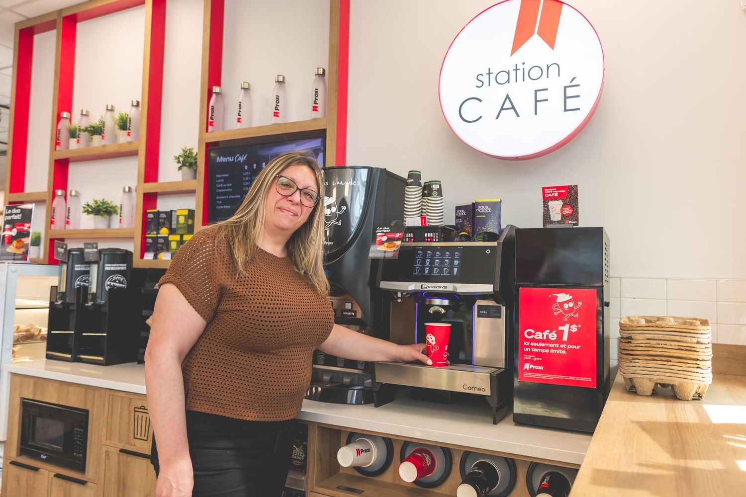 Modern cafe interior with red accents shows coffee machines and equipment arranged along a white counter.