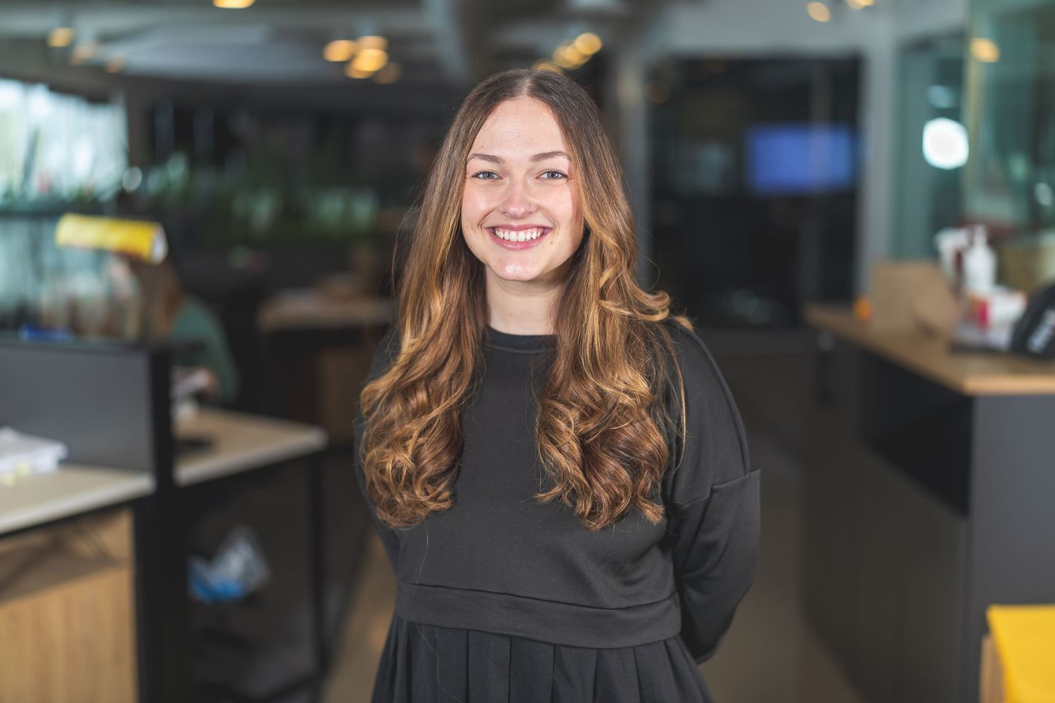 Professional portrait in modern office environment with dark lighting.