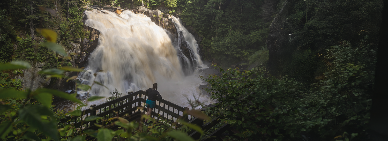 Scenic waterfall cascading through lush forest with wooden viewing platform.